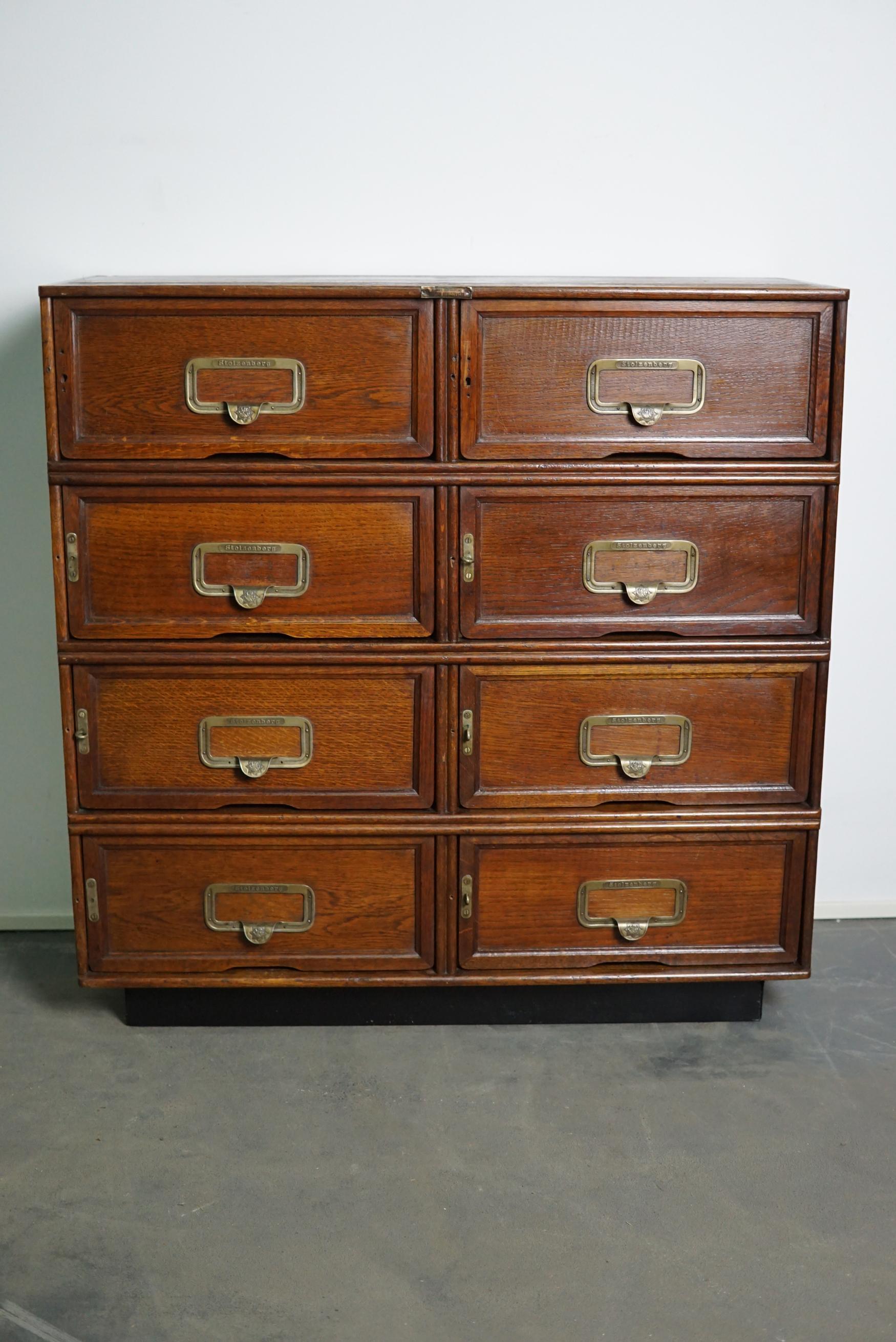 This filing cabinet was made circa 1930s in Germany. It features eight folding doors with very nice pulls / name card holders with the name and company logo of the brand Stolzenberg. The interior dimensions of the compartments are: DWH 30 x 38 x 15