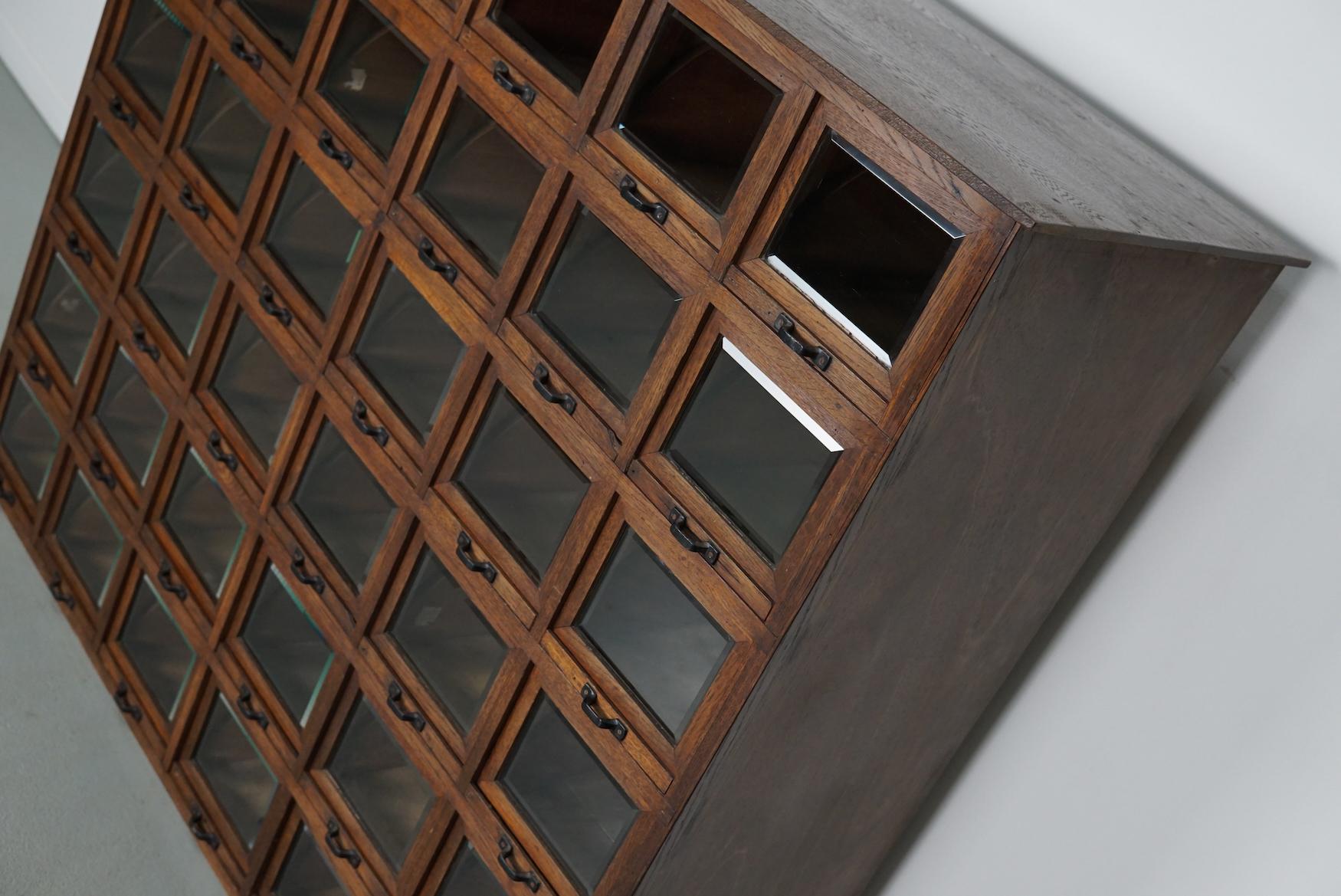 This very unique haberdashery cabinet was produced during the 1920/30s in Germany. It features 36 drawers with cut glass fronts / folding doors and black metal handles. It was originally used in a store for sewing supplies in Cologne. The interior