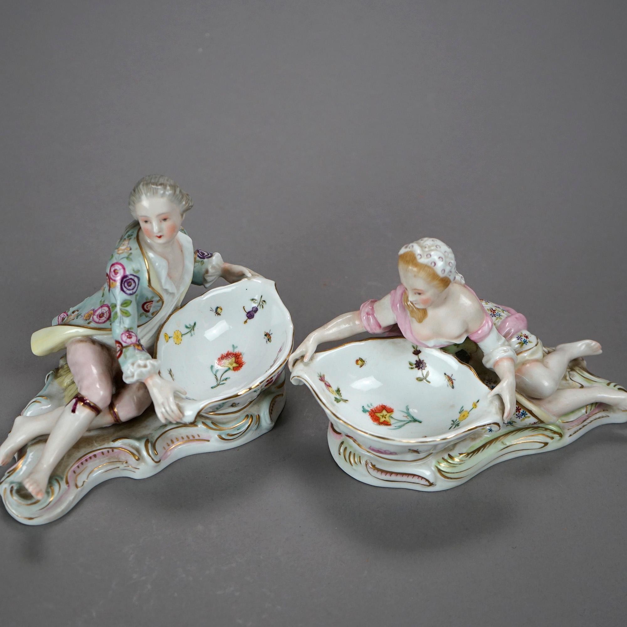 An antique pair of .figural sweet meat dishes in the manner of Meissen offer porcelain construction with hand painted and gilt figures of a woman and man, floral highlights throughout, maker mark on bases as photographed, c1900

Measures- 4.5''H x