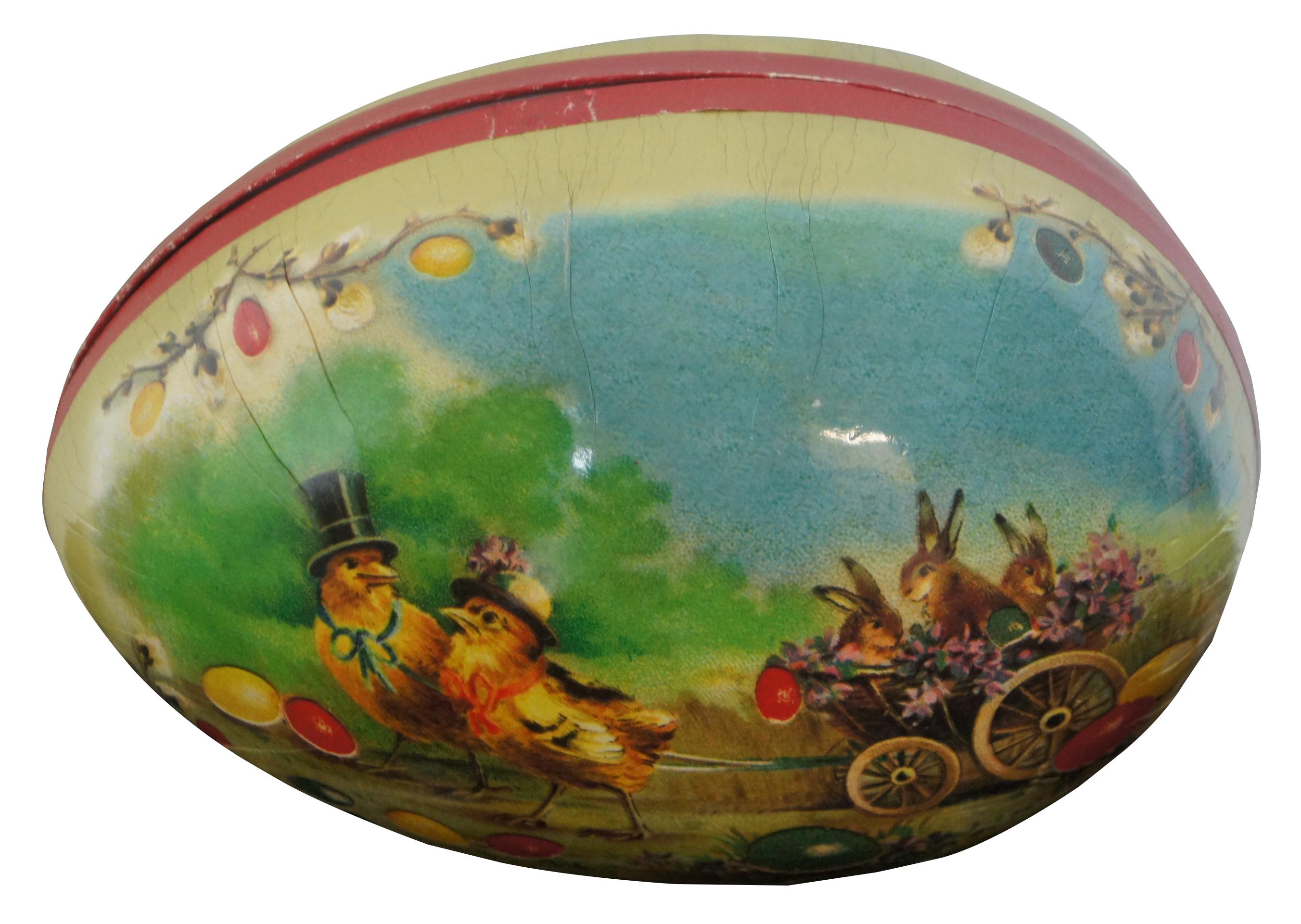 Antique German papier mâché Easter egg candy container, featuring a lithograph landscape with Easter eggs and pair of chicks in their Sunday best hats pulling a small cart containing flowers and three bunnies. Measure: 7”.
 