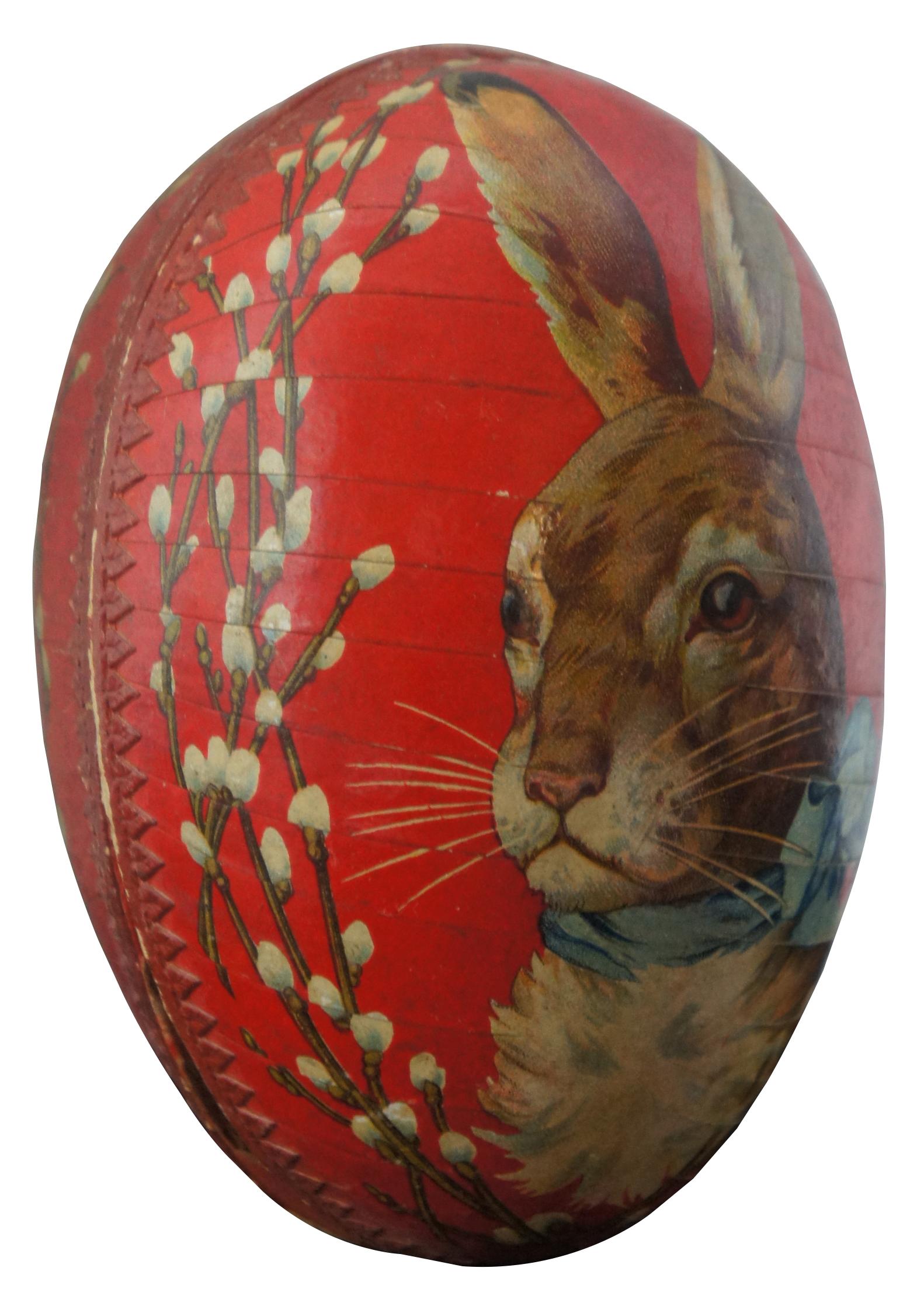 Antique German papier mâché Easter egg candy container, featuring a lithograph of a rabbit wearing a blue bow, framed by pussy willows, with paper lace trim around the inside edge. Measure: 4.5