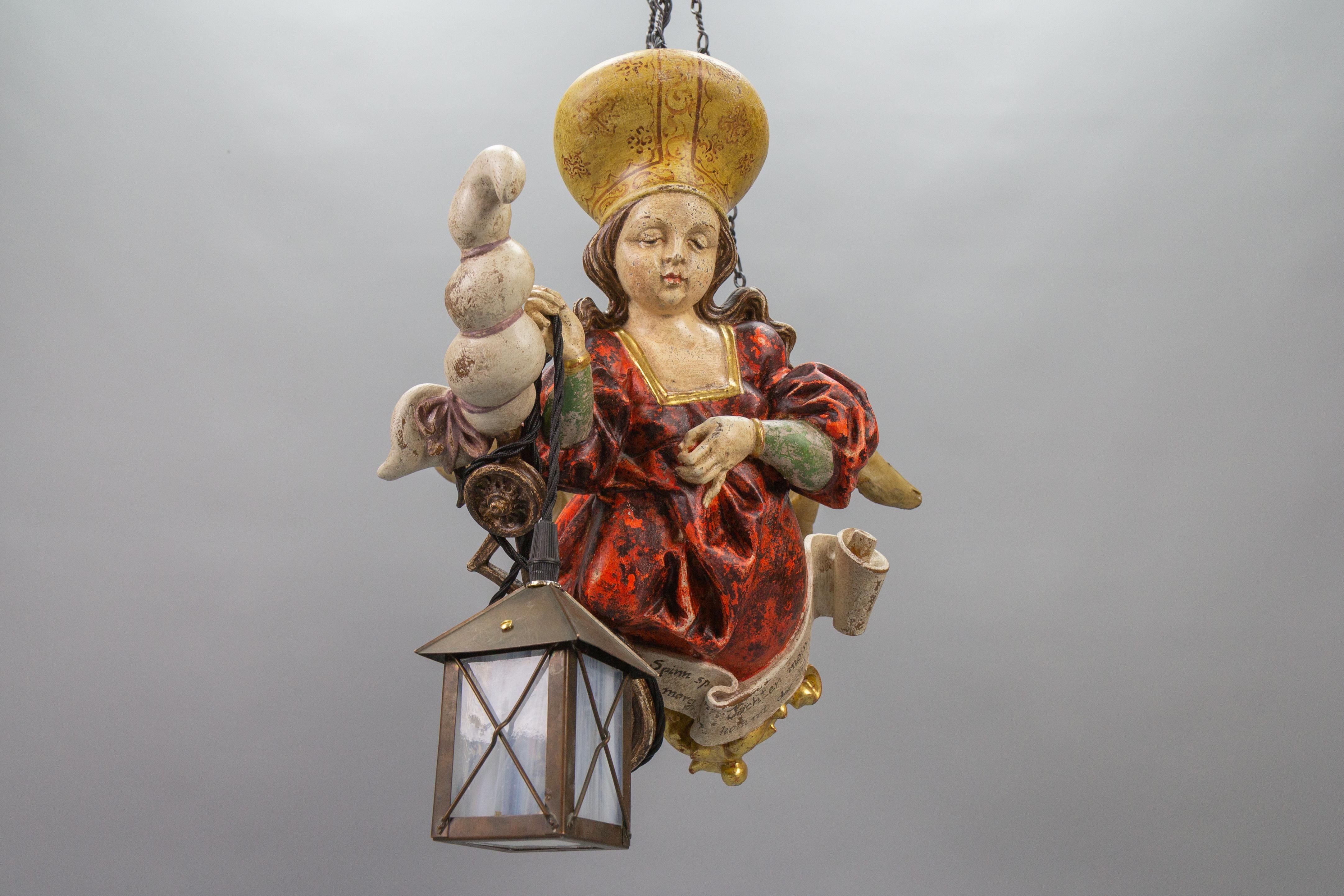 Antike deutsche Pendelleuchte Holz Polychrome Lüsterweibchen mit Laterne, von circa 1920.
Dieser bezaubernde Lüsterweibchen-Kronleuchter in kompakter Größe zeigt eine meisterhaft geschnitzte Figur einer jungen Dame in einem roten Kleid mit einem