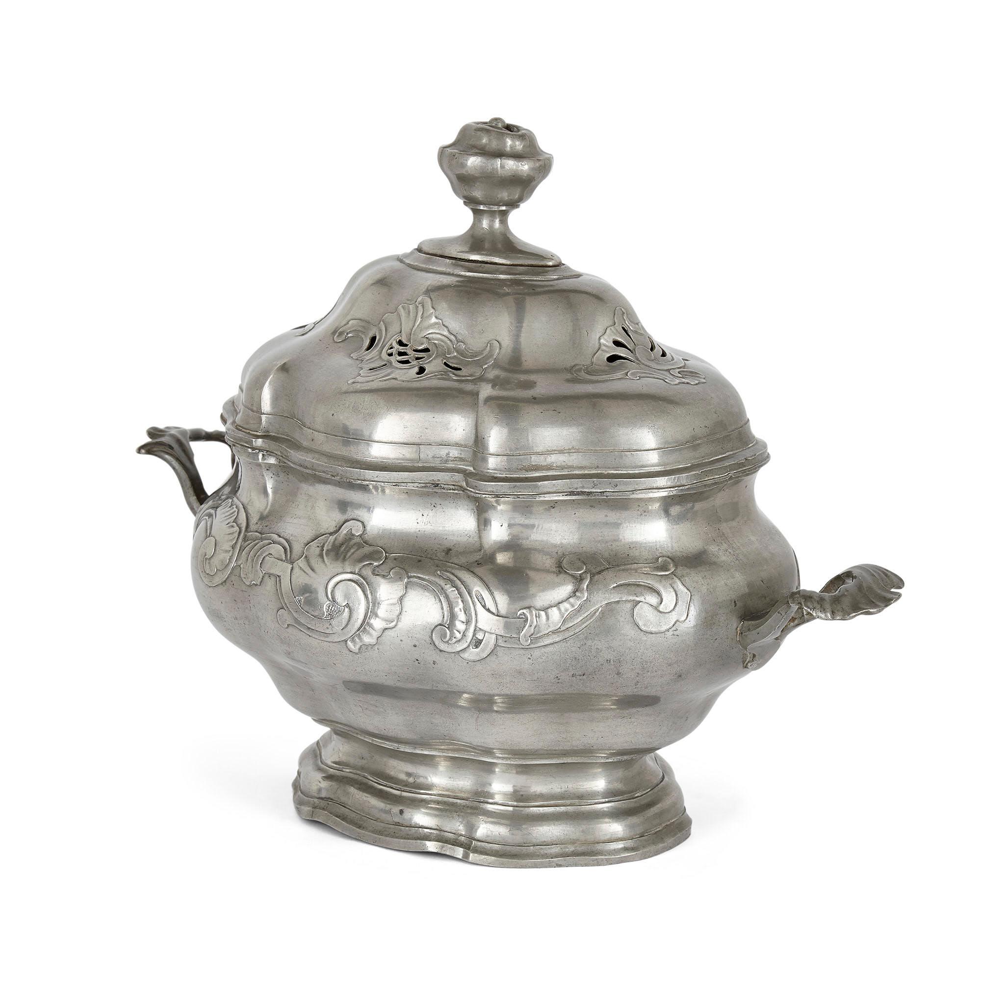 Antique German pewter bowl with pierced lid
German, 19th Century
Measures: Height 29cm, width 36cm, depth 21cm

This beautiful pewter bowl features a shaped body finished to the front and reverse with an embossed frieze of foliage, while each