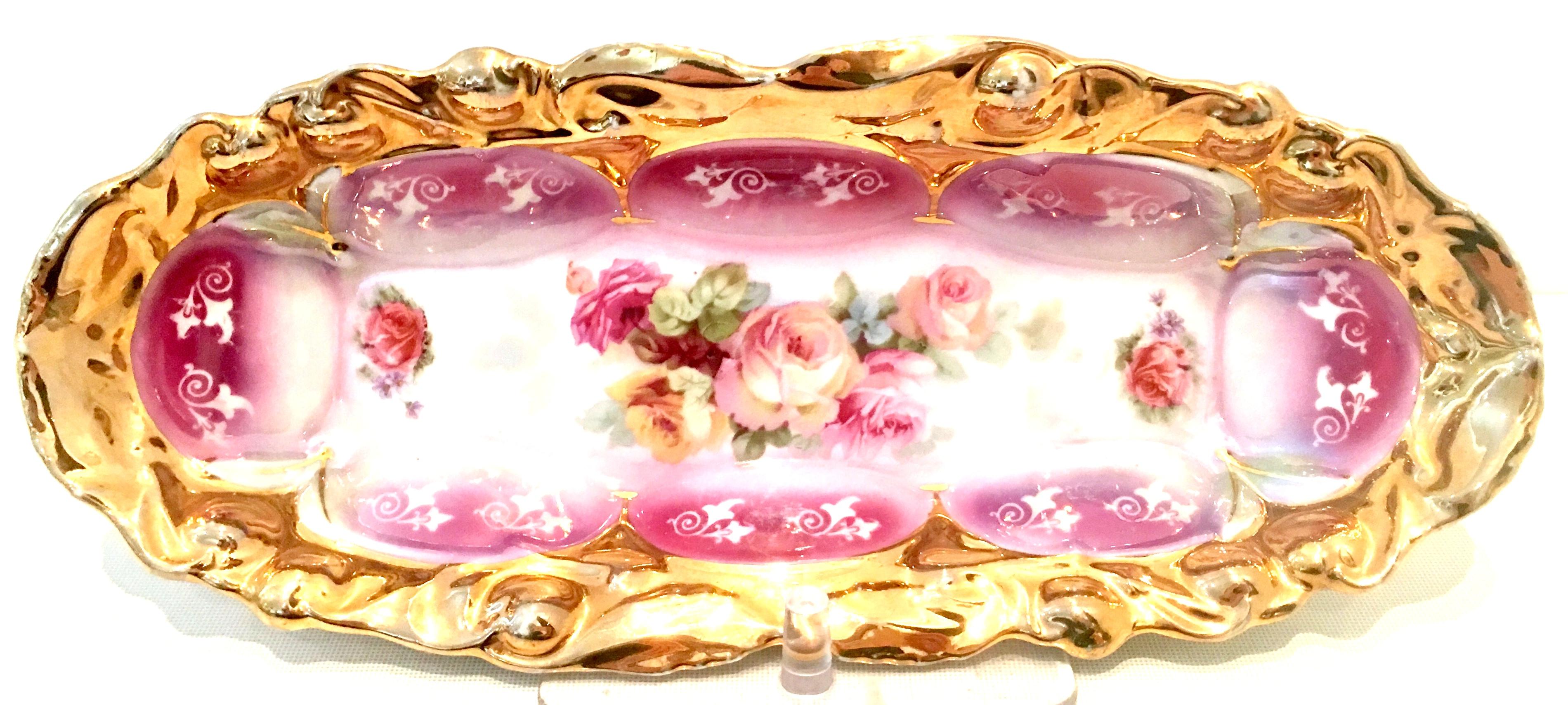 20th Century German porcelain hand painted 22-karat gold rose motif oval dish. Features a white ground with vibrant pink, green and purple rose motif and heavily applied 22-karat gilt gold detail. Signed on the underside, made in Germany 13.
