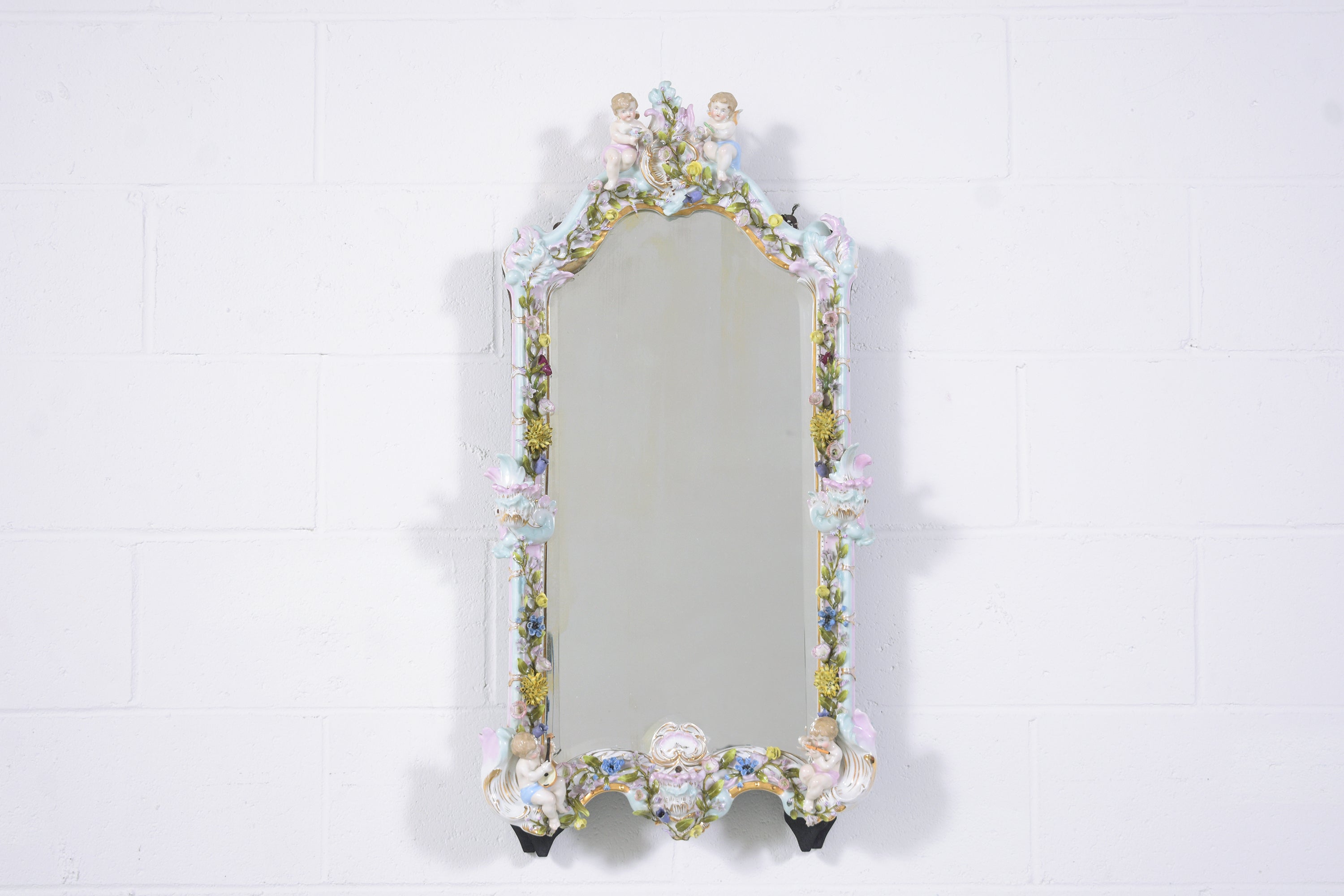 Embrace the elegance of our early 1900s Belle Époque style German mirror, masterfully crafted from porcelain and in very good condition. This remarkable piece showcases a richly detailed mirror frame, adorned with cherubs playing musical instruments