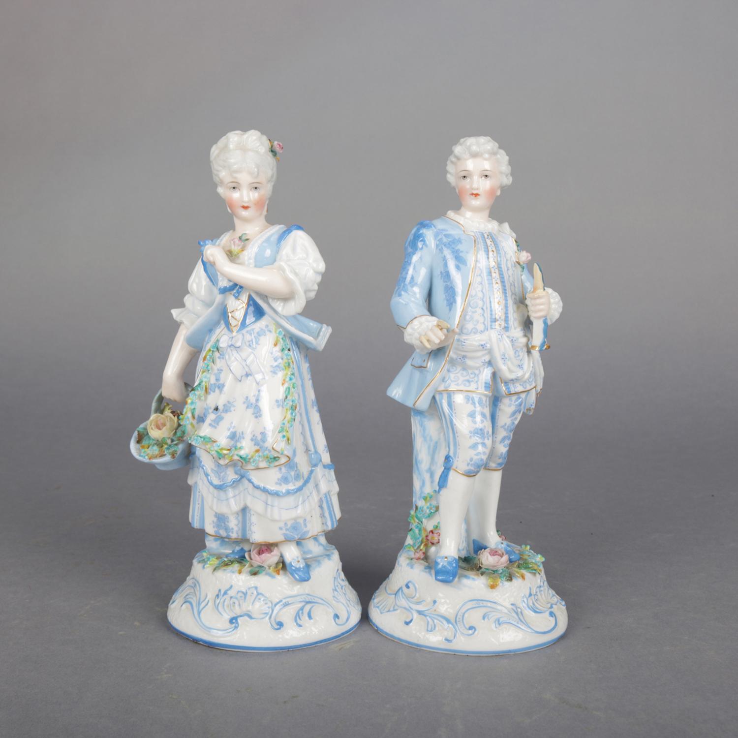 A pair of antique German Porzellanfabrik Unger Schneider CIE hand painted and gilt porcelain figures of courting couple in countryside setting, primarily blue and white, 