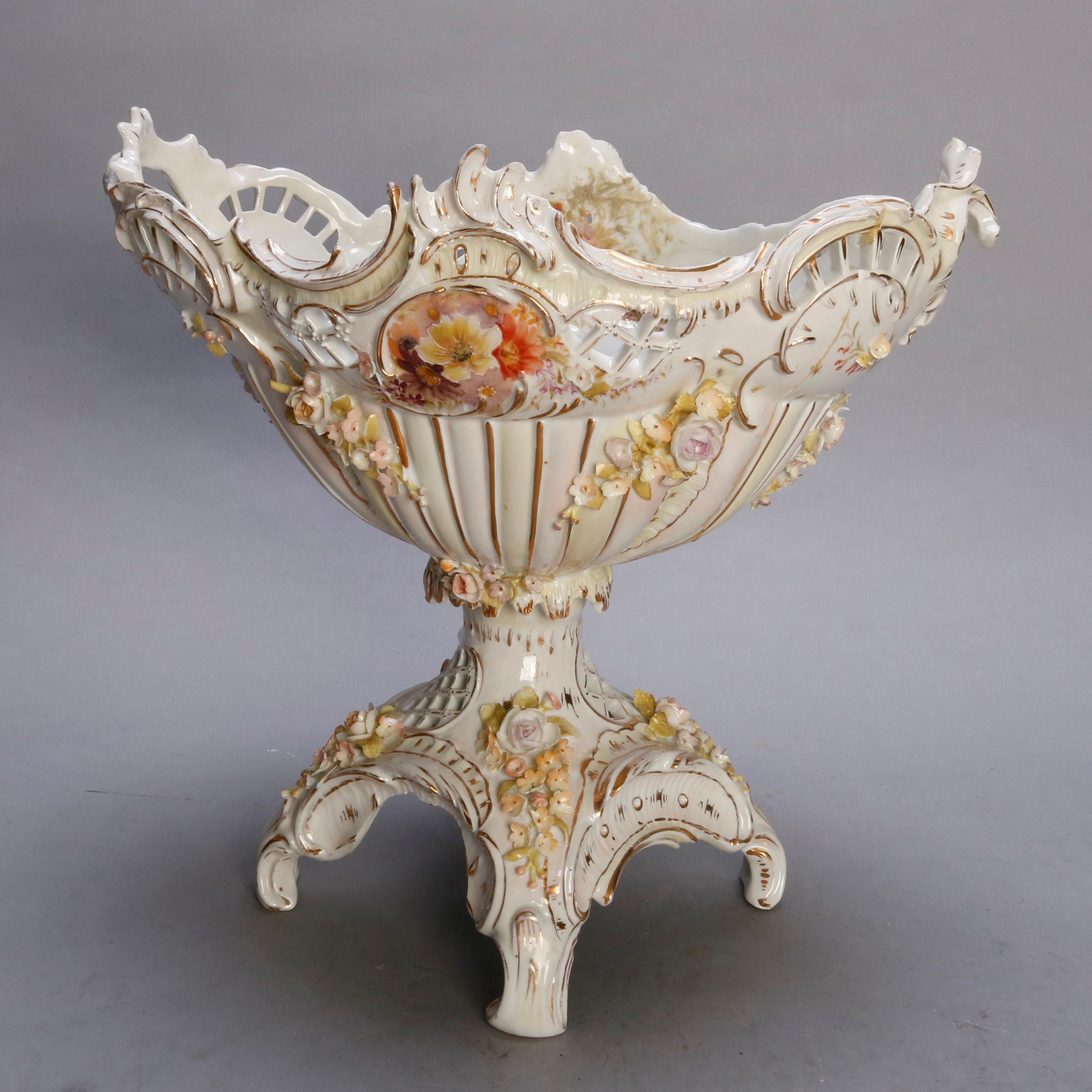 An antique German Rococo compote by Meissen offers porcelain construction with pierced foliate and scroll form bowl surmounting footed base with cherub, allowver hand painted and gilt floral decoration, marked on base as photographed, circa
