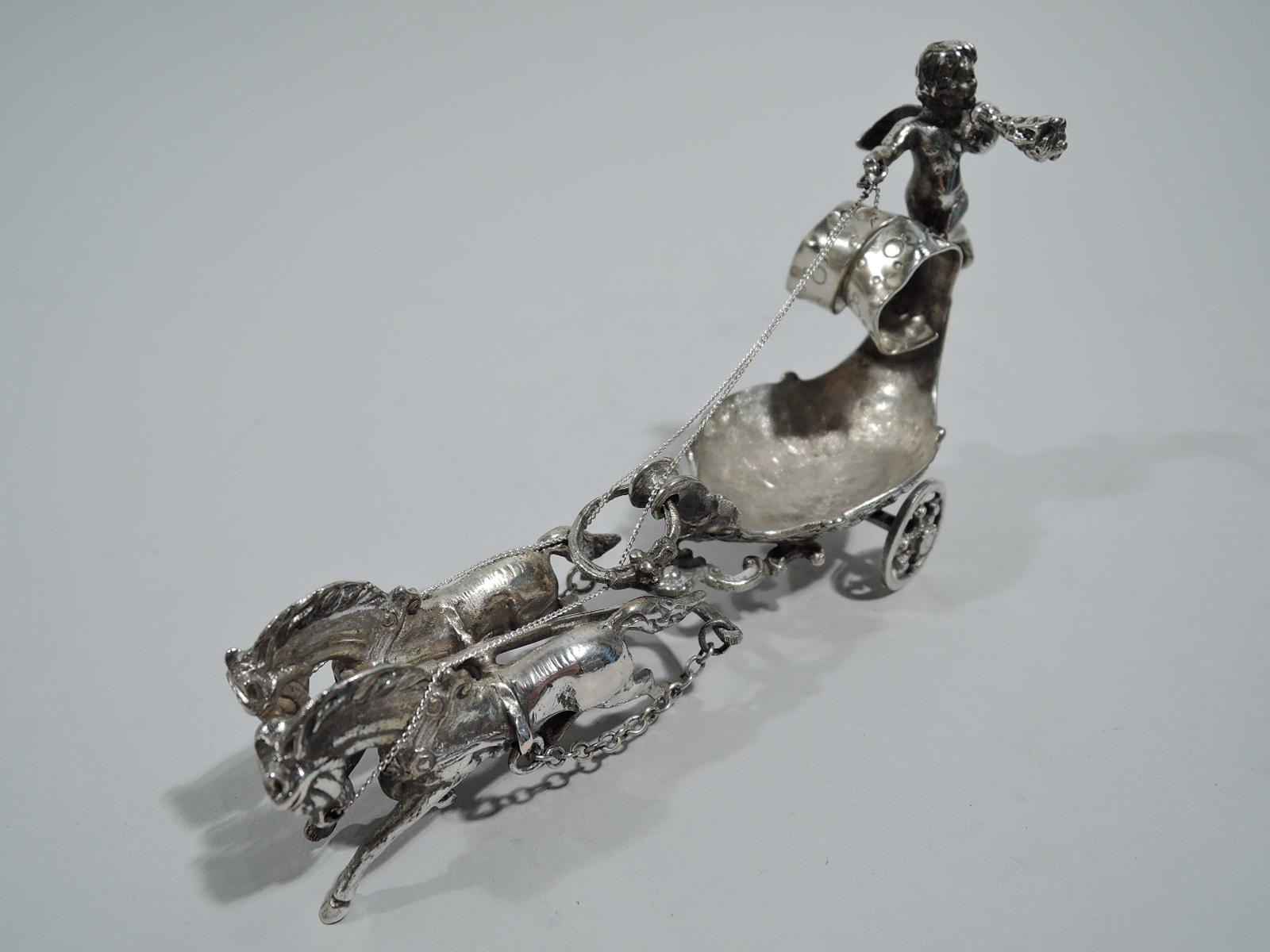 Turn-of-the-century German Rococo silver open salt. In form of shell-form coach harnessed to a pair of galloping horses. A cast cherub kneels on the scrolled back, gripping the reins and blowing a conch horn. Wheels rotate. A fantasy vehicle for