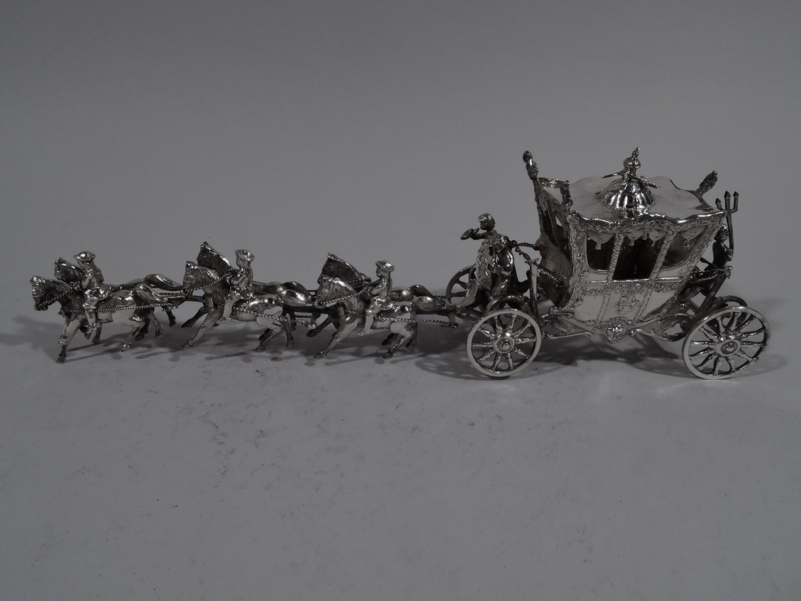 Turn-of-the-century German 800 silver coach-and-six. Exterior decorated with garlands, masks, and dragon-slaying knights. Windows hung with swags. Cover is mounted with crown, scepter, and cross, and is detachable. Horn-blowing caryatid coachman and