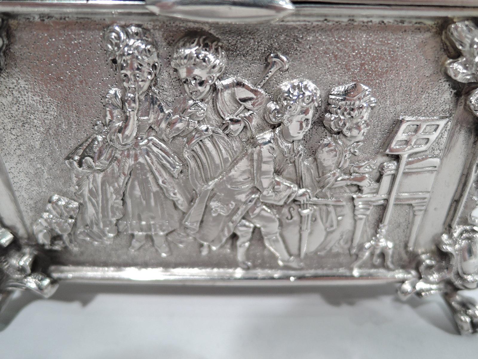 German Rococo 930 silver trinket box. Rectangular with straight sides and chamfered corners with wing-mounted monopodia supports. Cover hinged and raised with cast figural finial of boy in tricorn hat. Eighteenth-century scenes on sides. On front