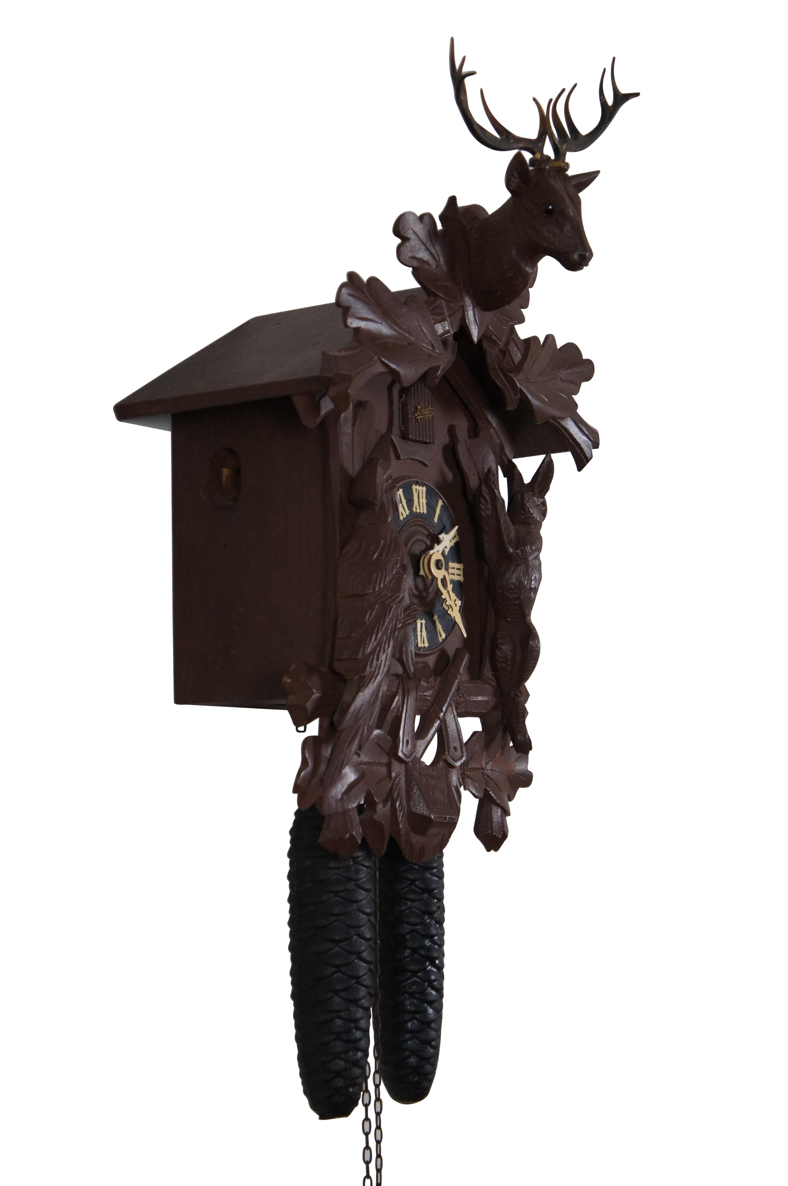 Antique German Schatz & Sohne Black Forest eight day cuckoo clock.  Features hunt / game / taxidermy theme with carved deer / stag , rabbit, bird and mantel with gun and tote.  Cast iron acorn weights.

Schatz Clock Company aka Jahresuhrenfabrik