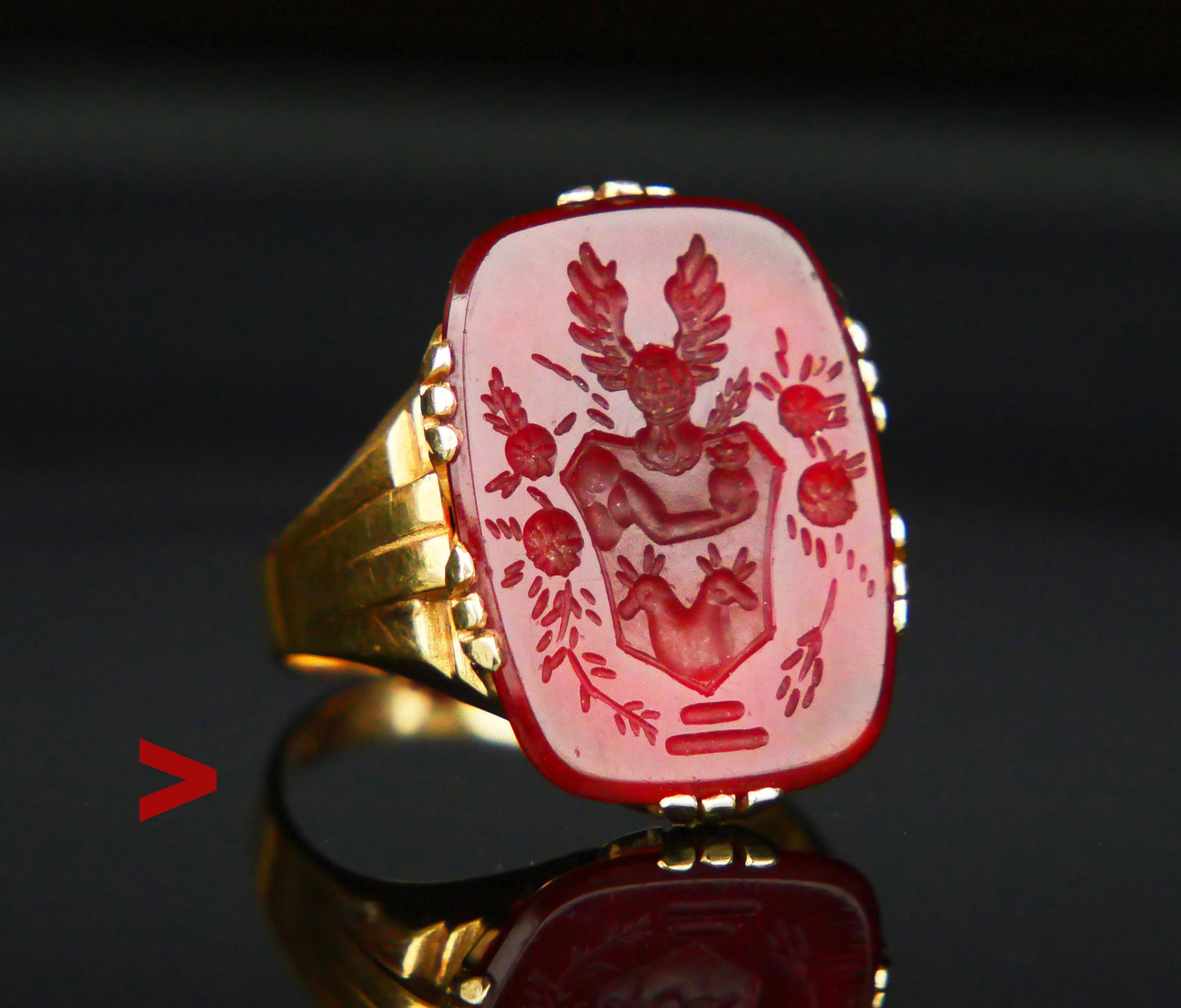 Old German Signet Intaglio Ring featuring claw set dark red Carnelian stone with hand-cut heraldic depiction of a king's right arm resting in the cloud and holding a crowned orb over two cut and crossed hands on the shield under a Knight's Helmet