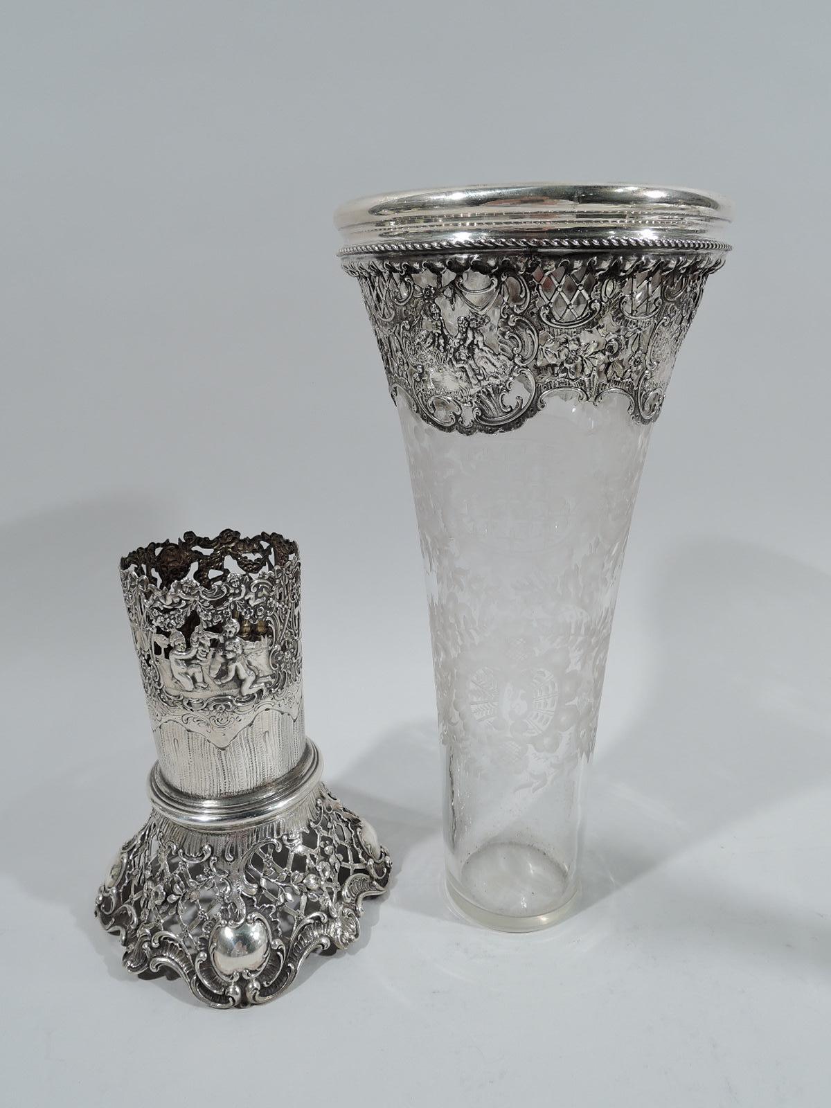 German 800 silver and glass vase, ca 1910. Tapering trumpet-form in clear glass with acid-etched wreaths, scrolls, and flowers. At top pierced and chased 800 silver mount with cherubs, flowers, and scrolls. Detachable 800 silver base with spread