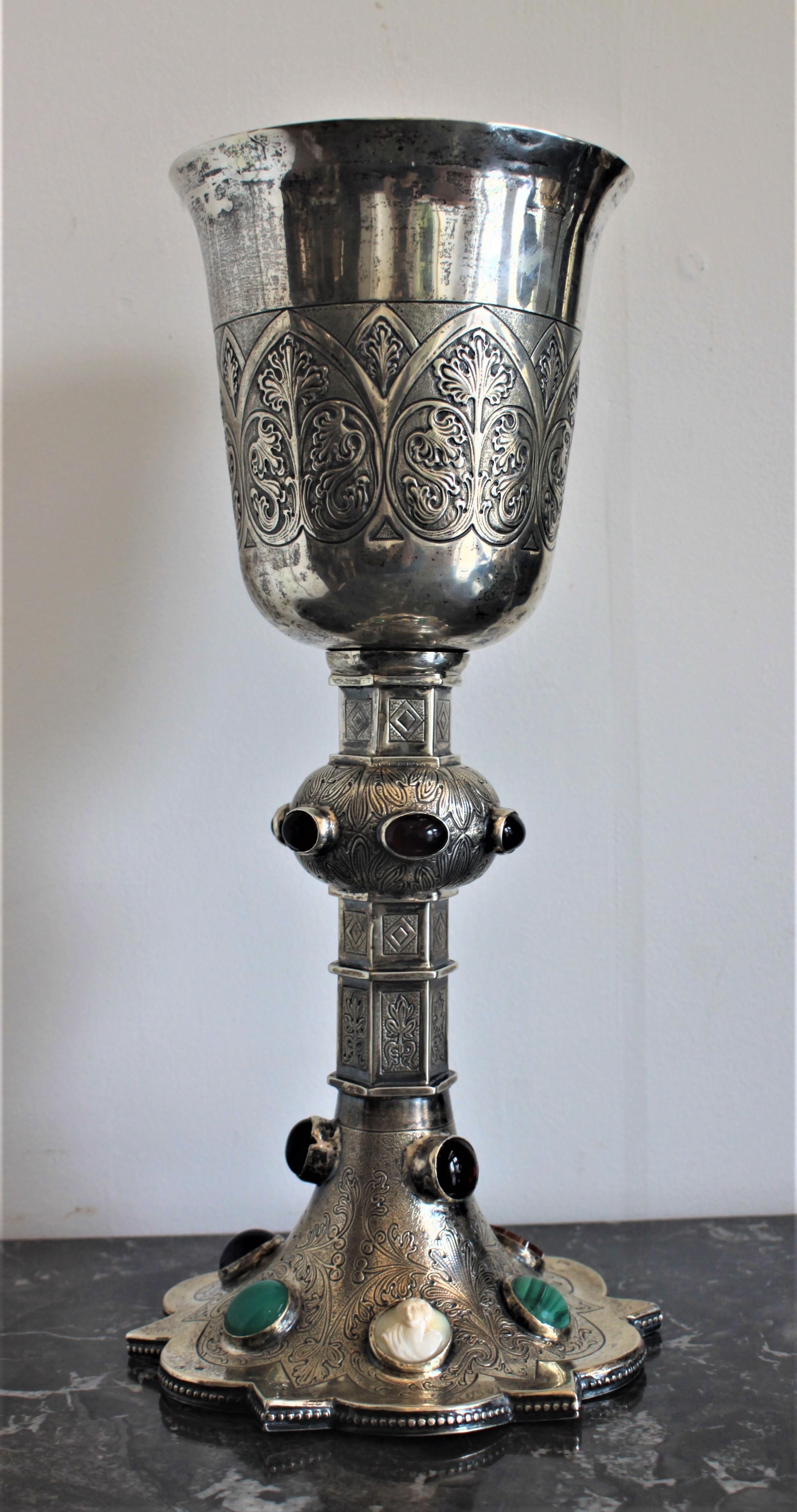 Dieser Kelch aus massivem 810er Silber stammt aus der Mitte des 19. Jahrhunderts und wurde in Deutschland hergestellt. Dieser Kelch ist von der Tasse bis zum Sockel kunstvoll graviert und hat mehrere geschliffene und polierte Halbedelsteine sowohl