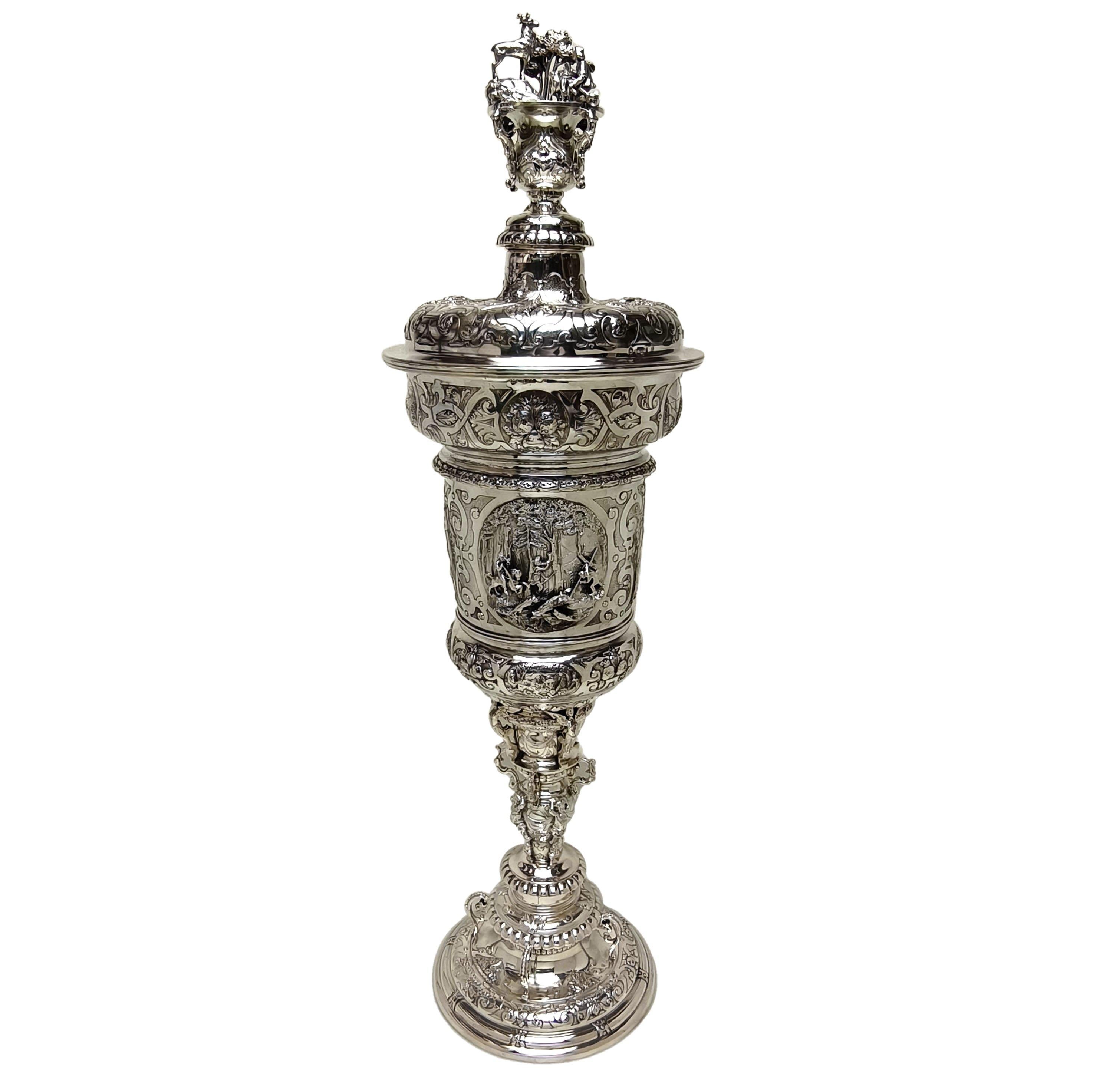 Eine prächtige antike deutsche Silber Tasse & Deckel in einem Historismus Renaissance-Stil. Diese hohe Tasse im Kirchturmstil ist mit einem kunstvollen ziselierten Muster mit Jagdmotiv verziert. Die monumentale  Die Tasse zeigt zwei große ovale