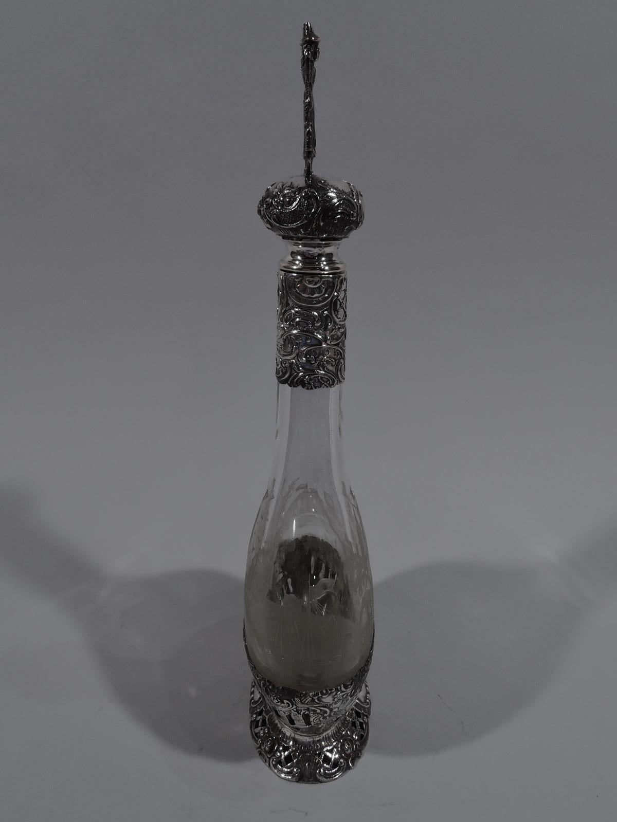 Carafe allemande en argent 800 et verre, vers 1910. Bol plat et rond avec col cylindrique. Paysages gravés à l'acide sur les deux faces, avec des moulins à vent, des ponts et des maisons pittoresques. Au bas 800 monture en argent avec des volutes