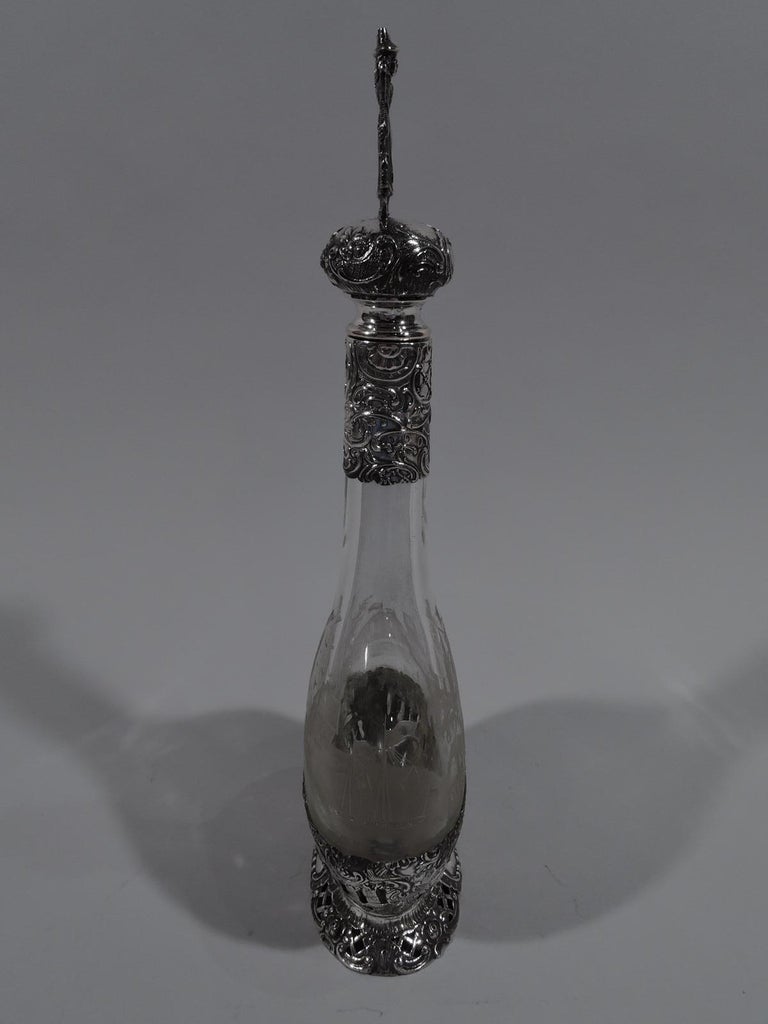 German 800 silver and glass decanter, ca 1910. Flat and round bowl with cylindrical neck. Double-sided acid-etched landscapes with picturesque windmills, bridges, and houses. At bottom 800 silver mount with pierced and chased scrollwork, as well as
