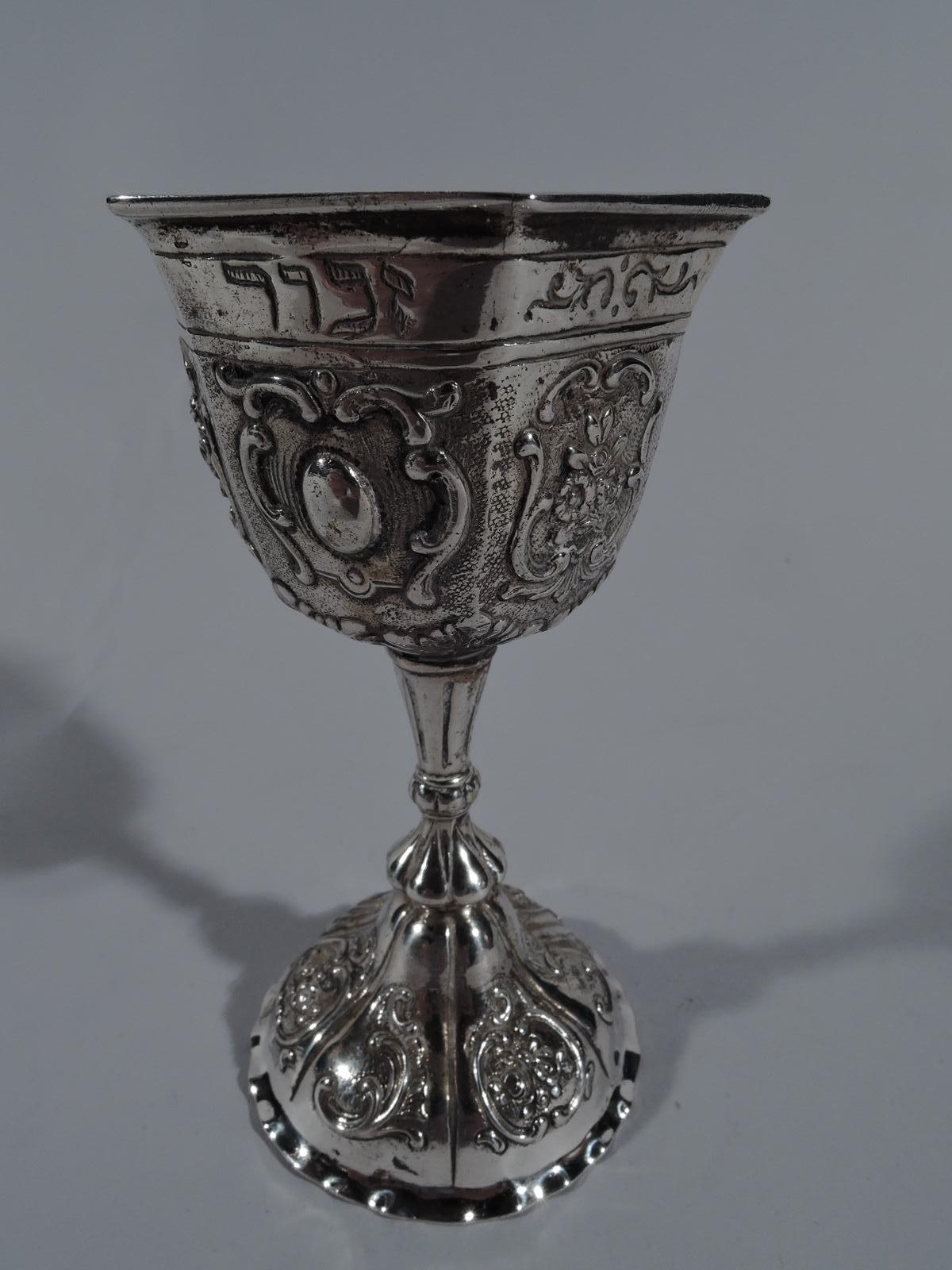 Antique German 800 silver Kiddush cup. Faceted bowl on knopped and tapering stem on domed foot with crimped rim. Chased scrolls and flowers. Engraved Hebrew at bowl rim. Marked. Weight: 3.4 troy ounces.