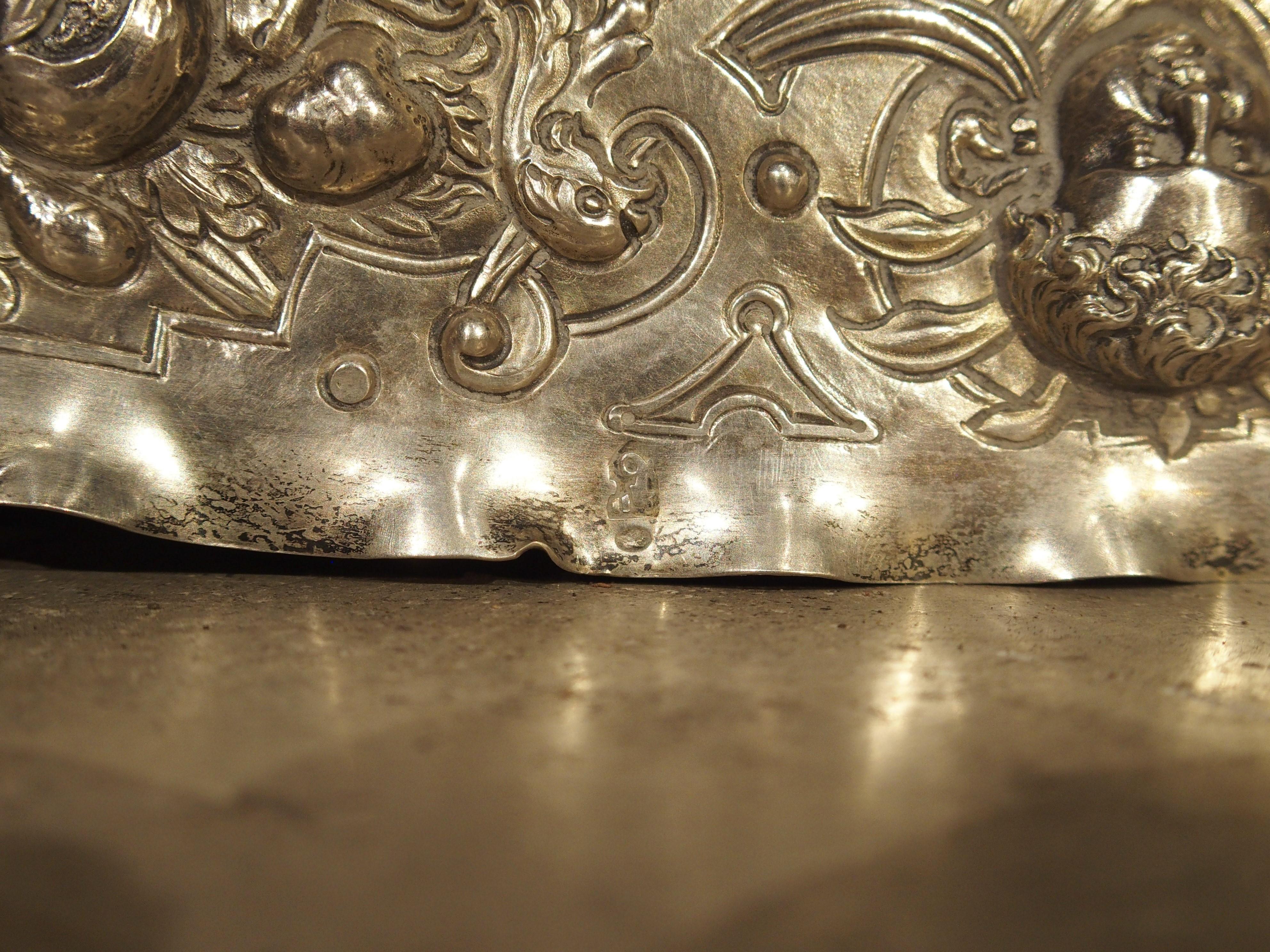 This richly decorated silver serving tray with repousse work is from Germany’s Gründerzeit period, circa 1850. The exquisite repoussage depicts an unknown military skirmish of soldiers with spears and swords on horseback. The chaotic action of the