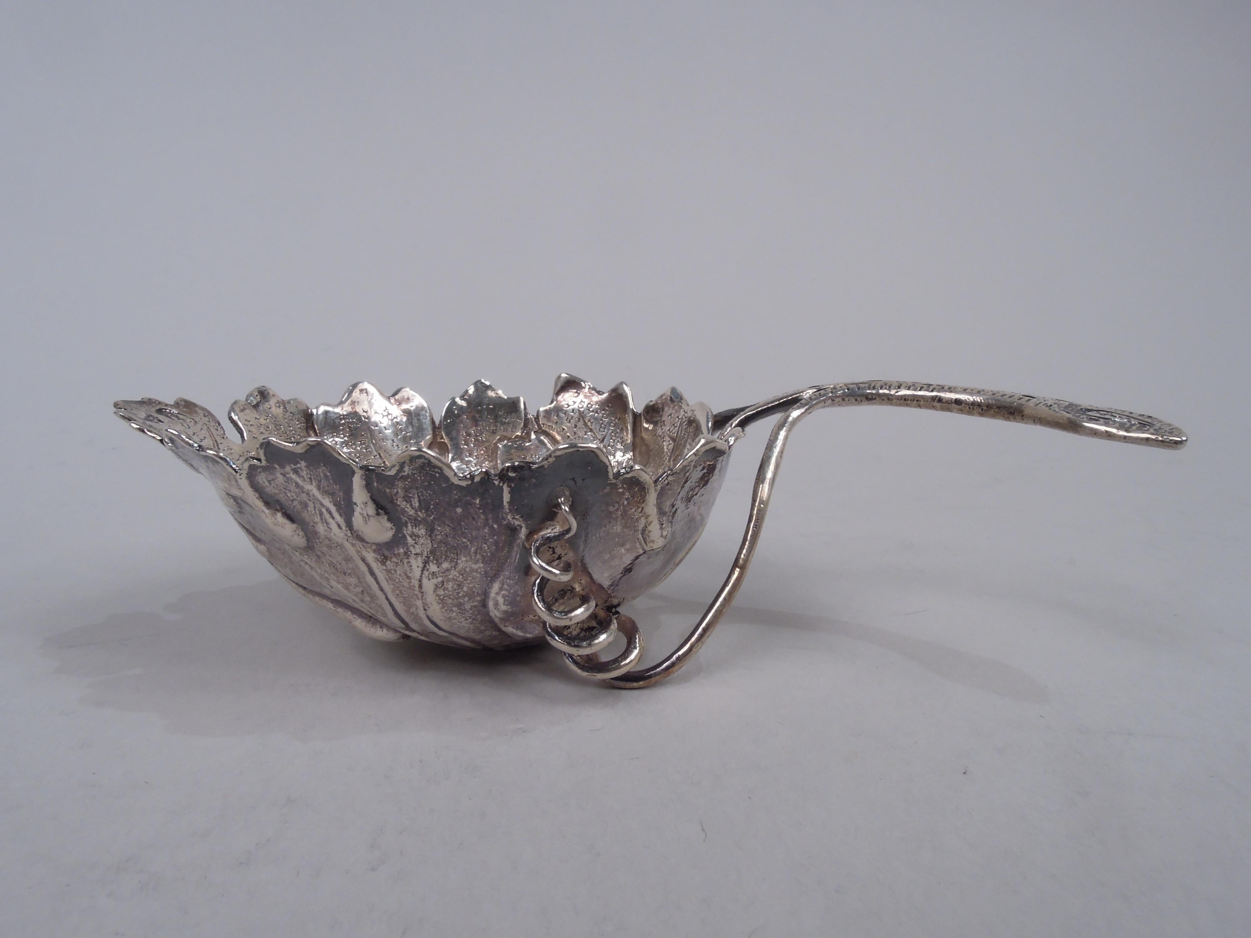 German silver tea scoop. Imported to England in 1892 by Thomas Glaser. Leaf-form bowl with veins and wispy, irregular tips. Woody stem with coiled tendril mounts. German marks and English sterling-standard import marks including London assay stamp.