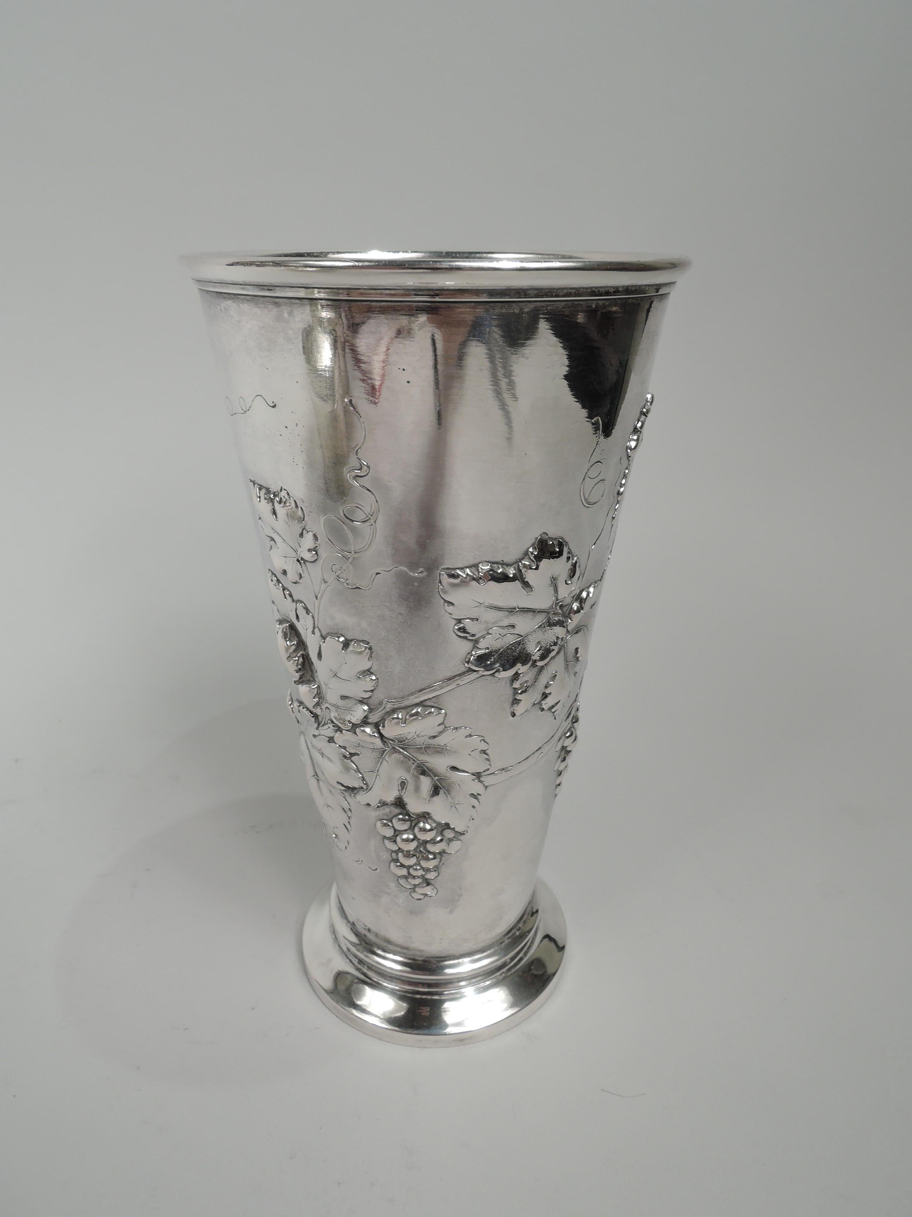 German 800 silver wine cup, ca 1910. Straight and tapering sides and raised and spread foot. Chased wraparound fruiting grapevine forming shaped cartouche (vacant). Tall and capacious with communal and ceremonial possibilities. Marks include maker’s