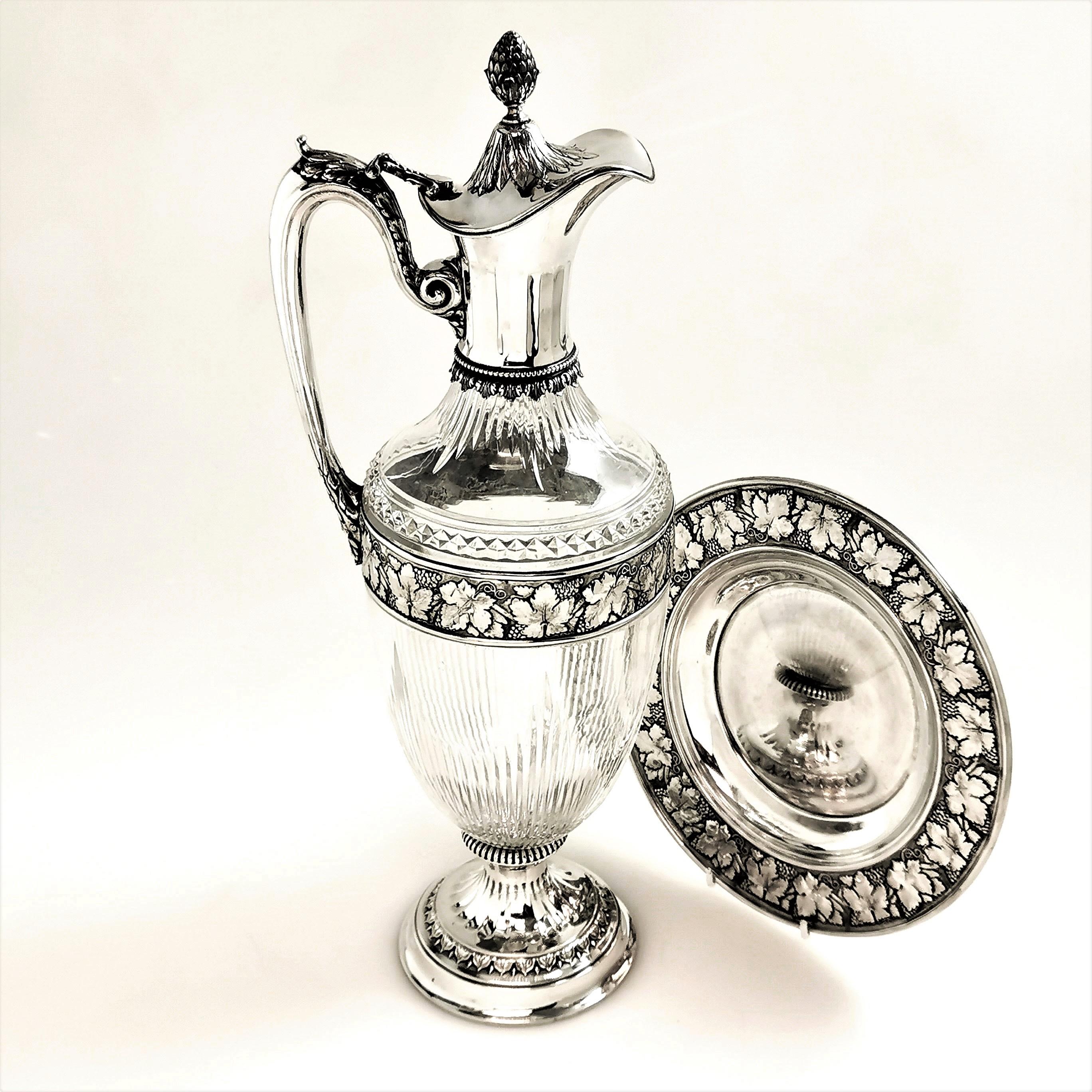 A magnificent Antique Silver mounted Claret Jug with an elegant cut glass body. The Wine Jug has band around the body with a chased grape and vine leaf design, mirrored on the chased rim of the under plate. The Claret Jug has a tall acorn finial on