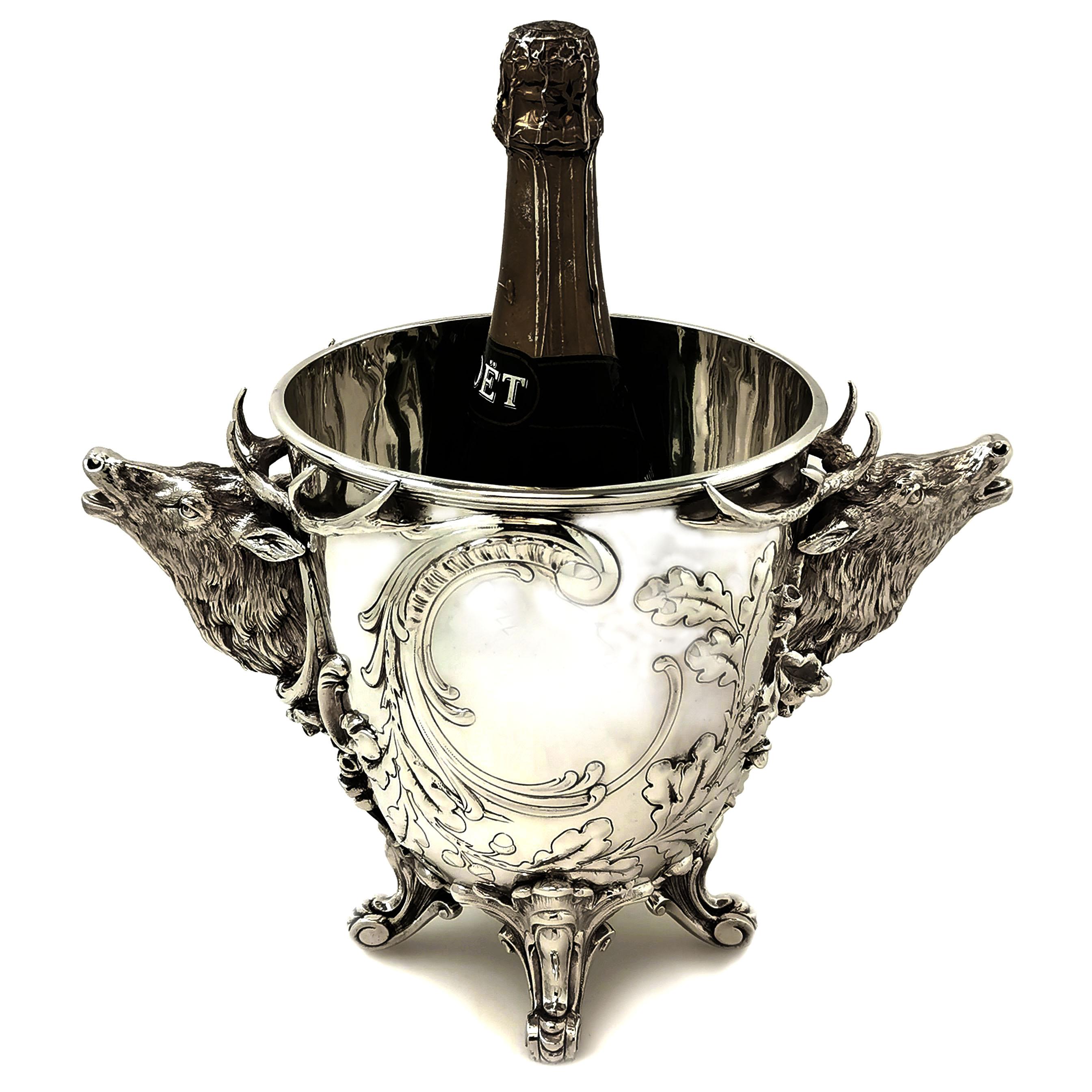 An impressive antique German solid silver wine cooler / Ice bucket featuring a pair of magnificent silver stag handles. The ice bucket stands on four scroll feet and the body of the cooler is embellished with chased oak leaf and scroll designs. The