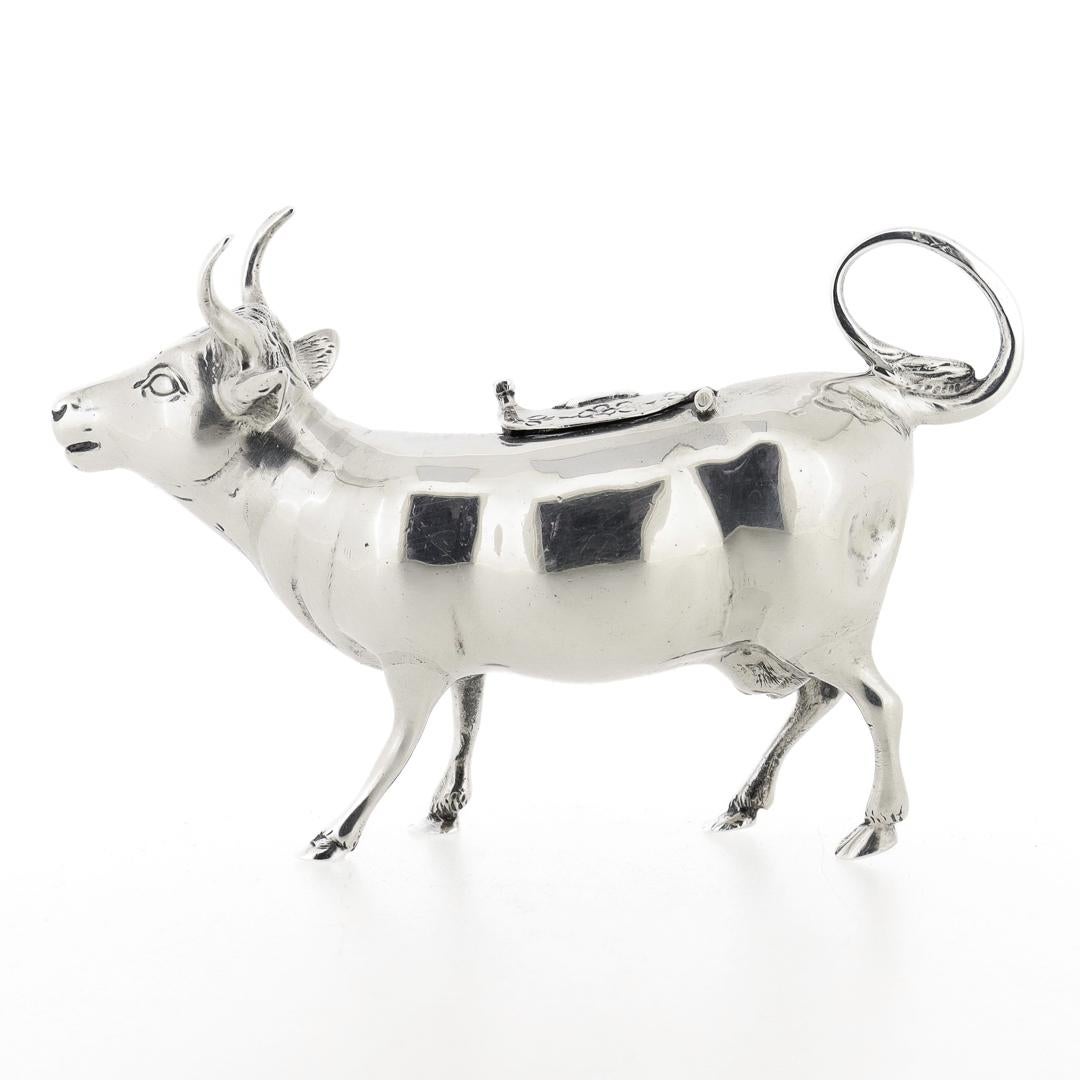 A very fine figural sterling silver creamer or milk pot.

In the form of a cow with a loop 'tail' handle, a hinged lid to the back, and a spout at the mouth.

A whimsical, figural creamer - perfect for any breakfast table!

Date:
20th