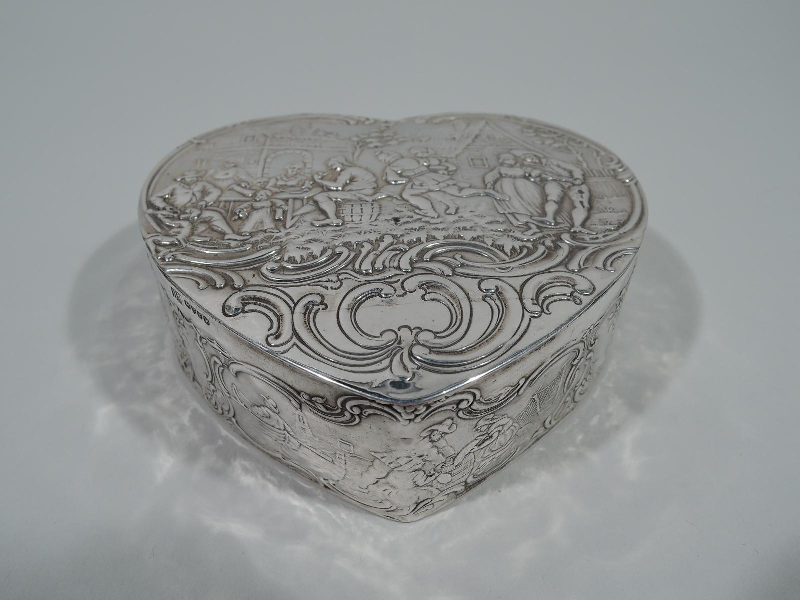German sterling silver heart box. Imported to England by Berthold Muller in Chester in 1904. Straight sides and flat hinged cover. Chased olden-days scenes with merrymaking and laboring peasants: Dancing and feasting as well as planting and fishing.