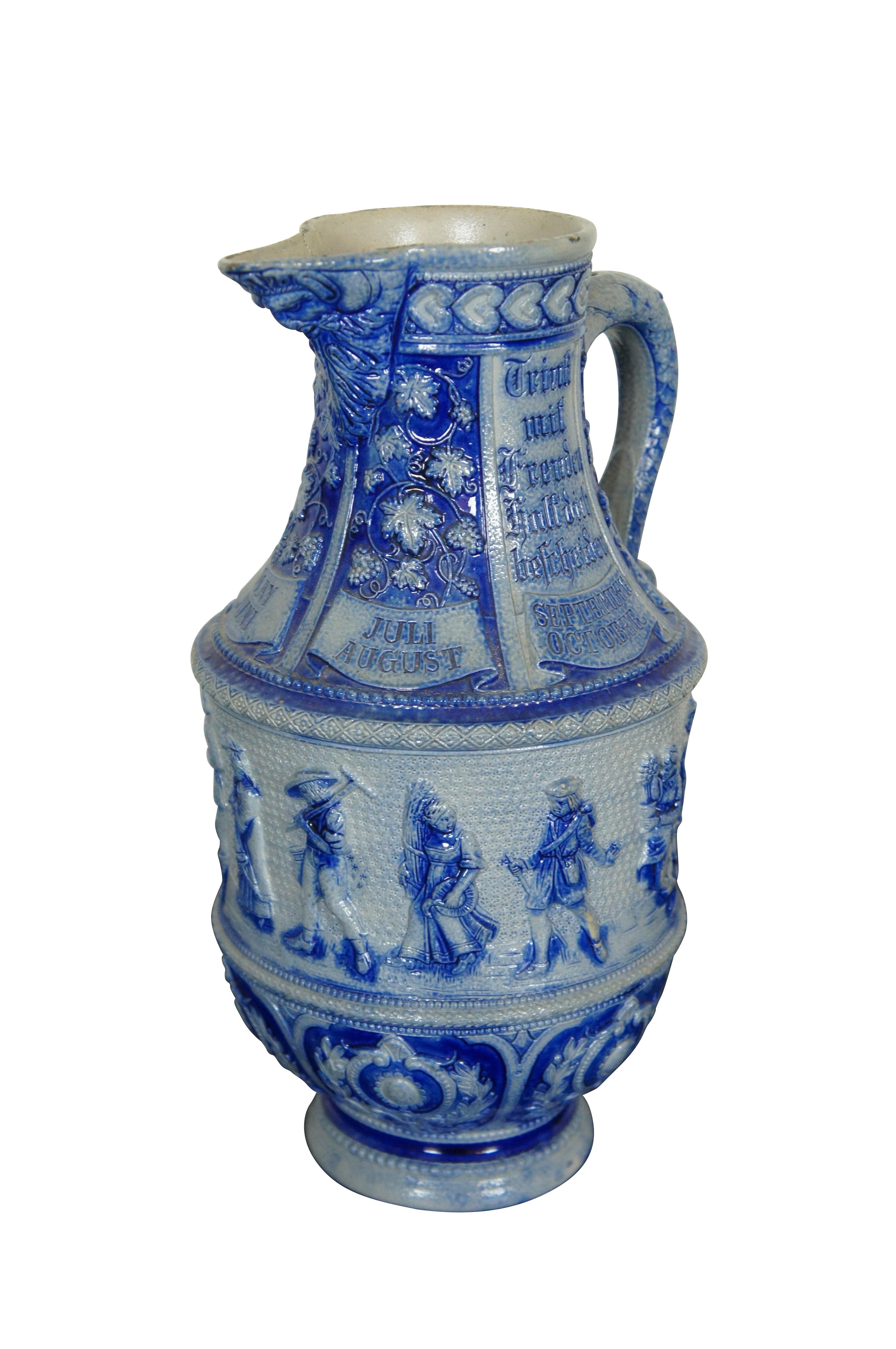 Antique German cobalt blue salt glaze stoneware pitcher / jug / ewer featuring the face of Dionysus or Bacchus - God of wine - on the spout surrounded by grapevines / grapes / leaves and the months of the year.  The handle has serpent scales and the
