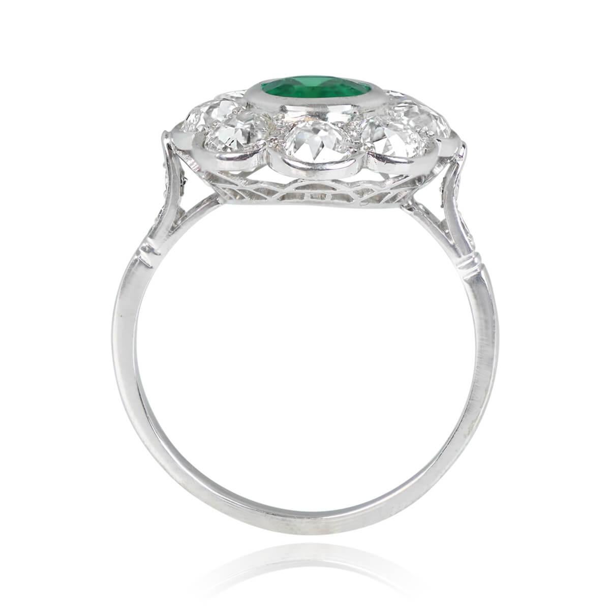 An alluring French antique gemstone ring showcases a 1.00-carat oval-cut natural Colombian emerald, set within a bezel. Encircling the gemstone is a floral halo composed of old European cut diamonds. Further enhancing the ring are single-cut