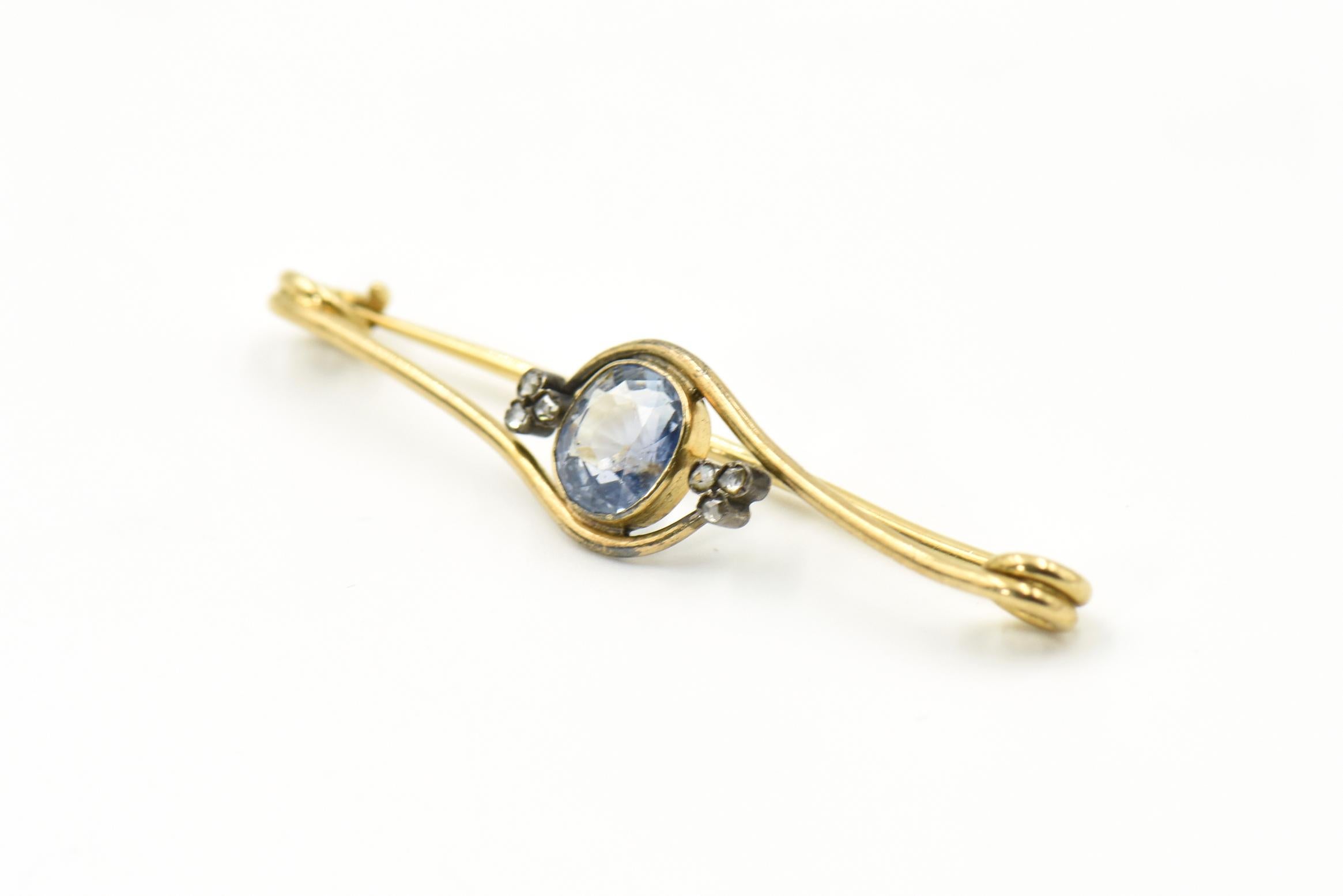 Antique bar pin featuring an antique cushion cut light blue faceted Sri Lanka Sapphire (approximately 2.59 carats) bezel set suspended by three leaf clover boarders terminating with rose cut diamond buds.   The edges are gold coils similar to a