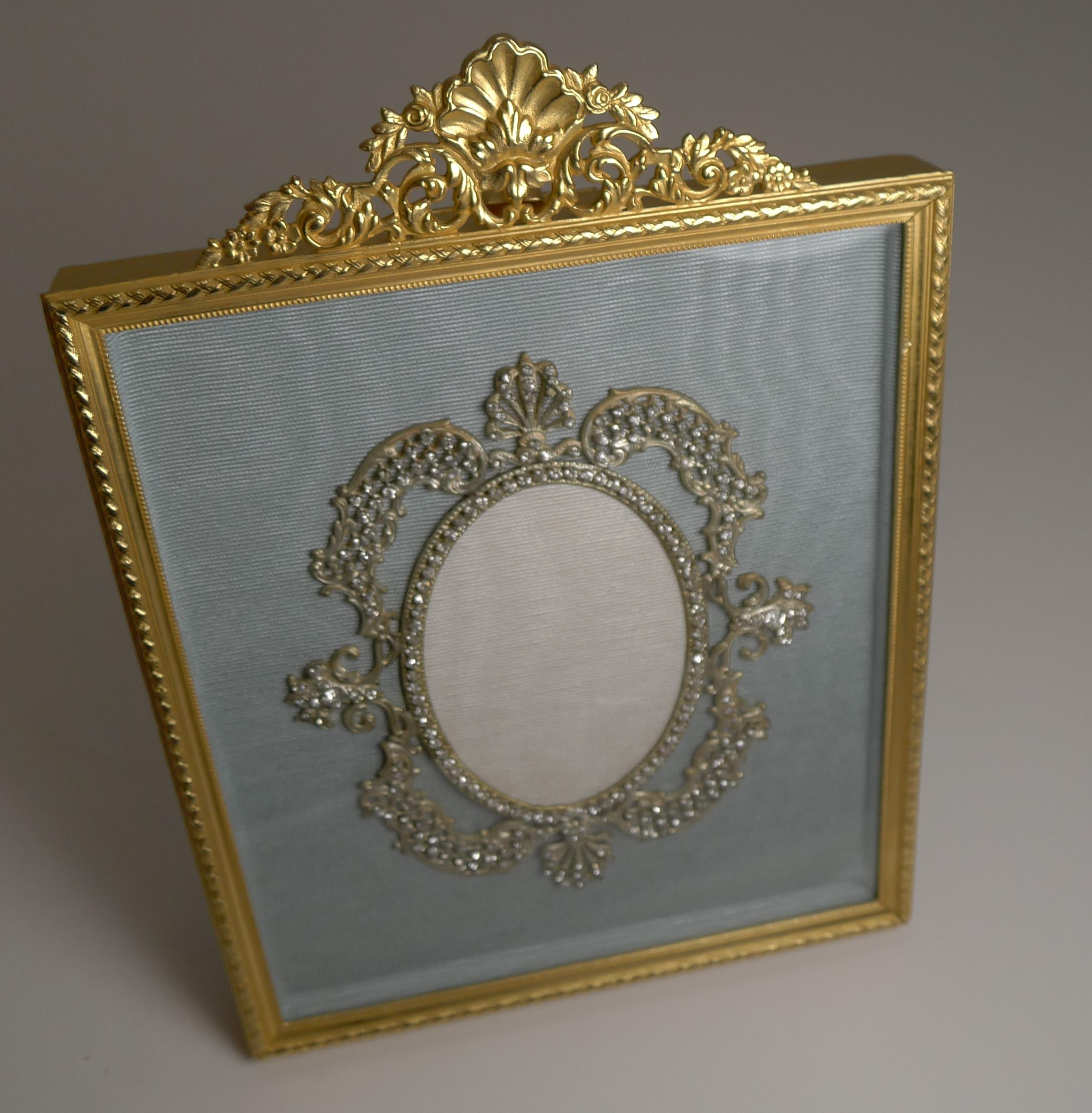 A most unusual late 19th-early 20th century French Ormolu picture frame made from bronze and lavishly decorated with gold, having been professionally restored to it's former glory.

The floating glass front protects the grey/blue silk taffeta and