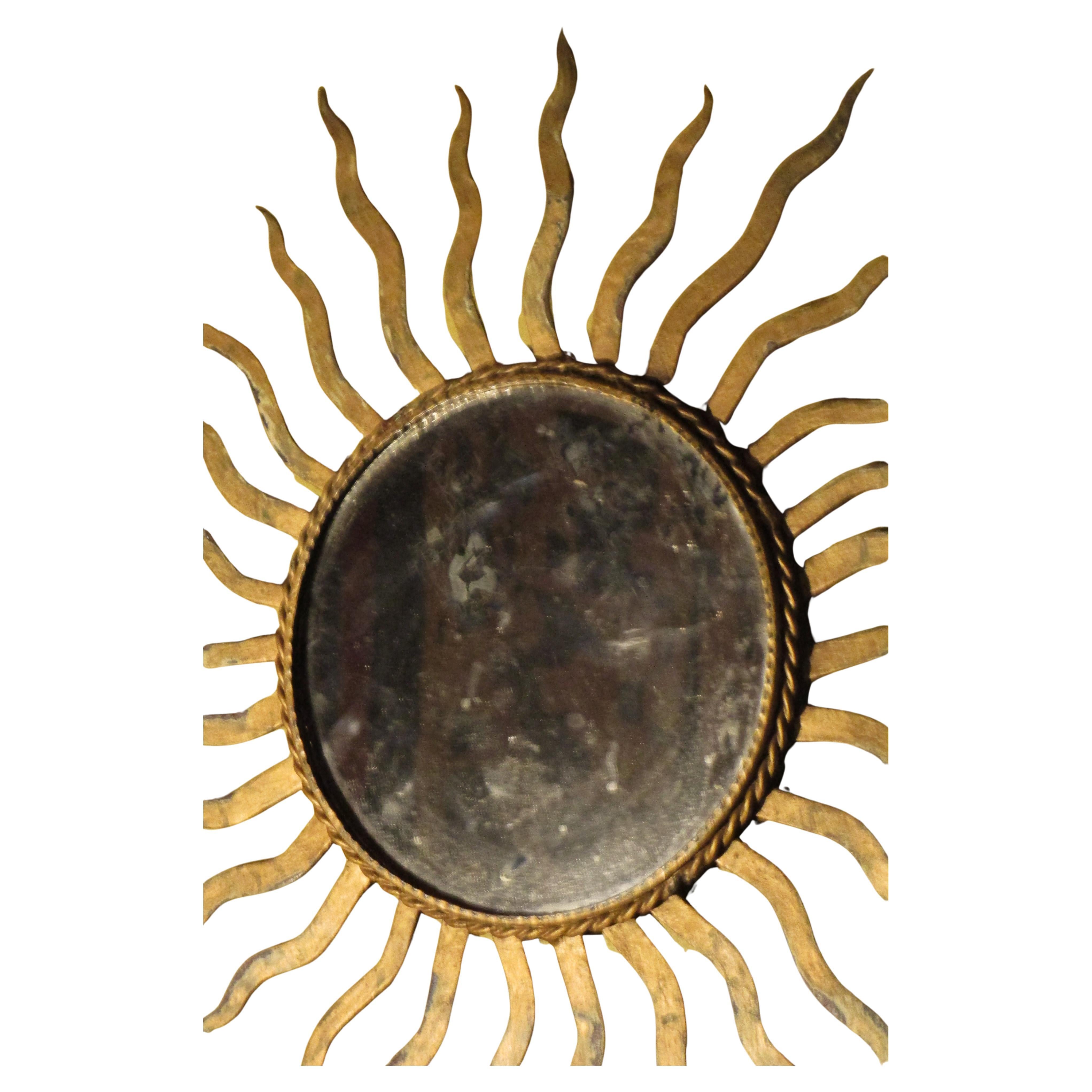 Antique iron sunburst mirror in the style of Gilbert Poillerat w/ nicely aged original old gilded surface. Beveled circular mirror  w/ oxidation to silvering. Iron ring on back for wall hanging, Mirror frame measures 21 1/2