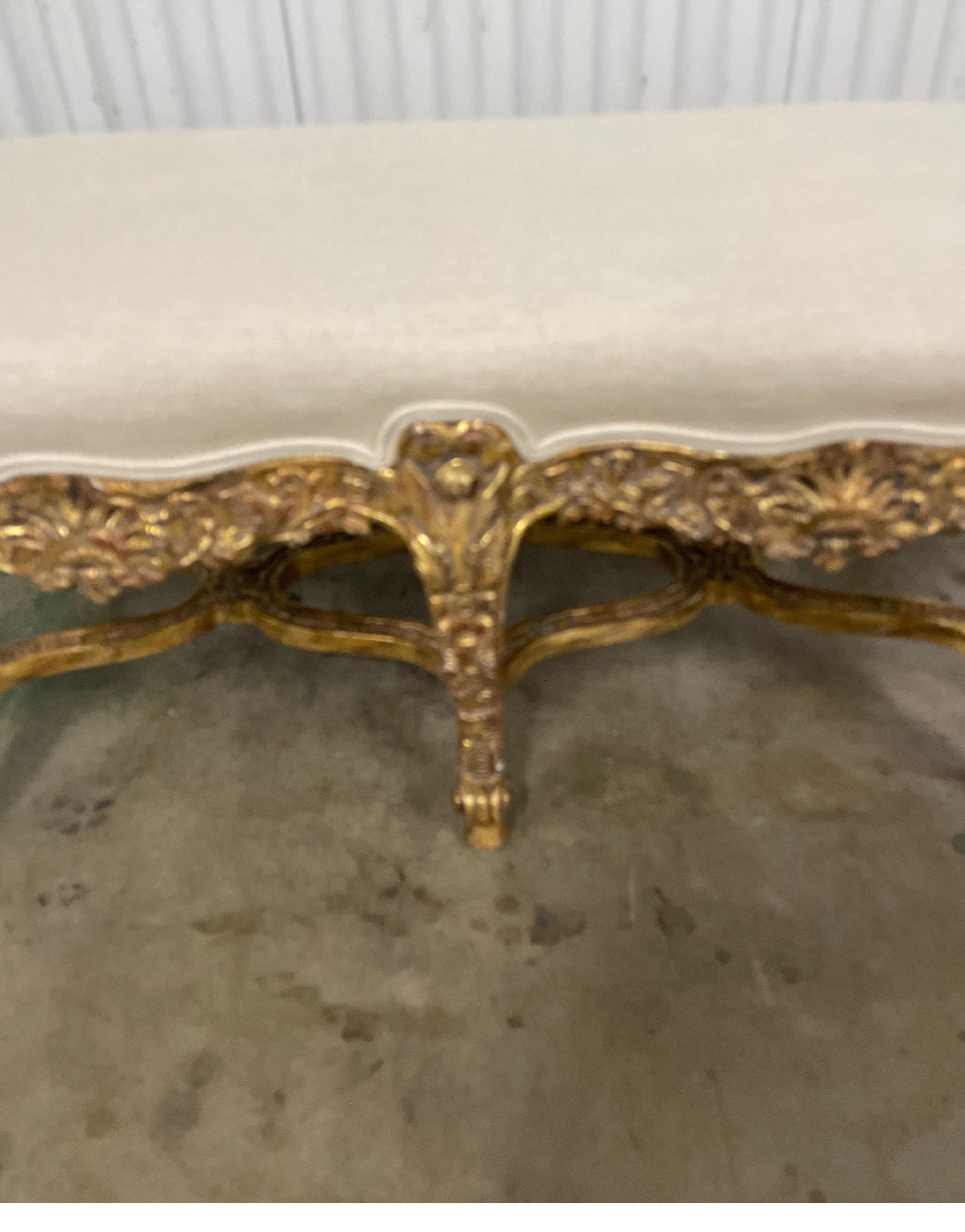 Antique Italian giltwood rococo style bench newly upholstered in a natural linen fabric. This stunning bench rests on six legs connected by an X stretcher. Intricate details and gilding.