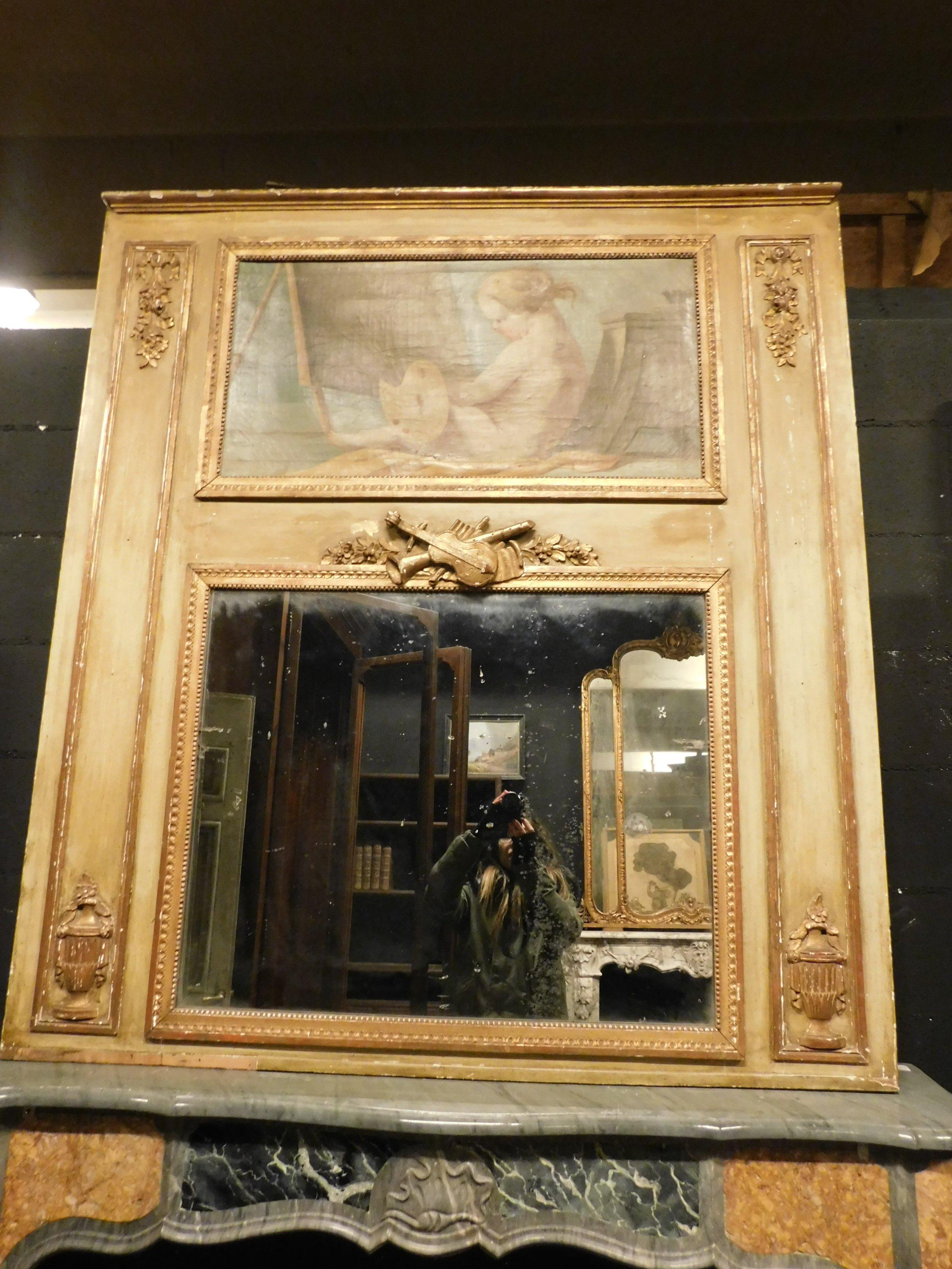 Ancient gilded and lacquered mirror with ocher yellow earth colors, original Louis XVI style with painting above, an entire mirror dedicated to art, in fact it has music in the decorations carved on the frame and the painting depicts a goddess who