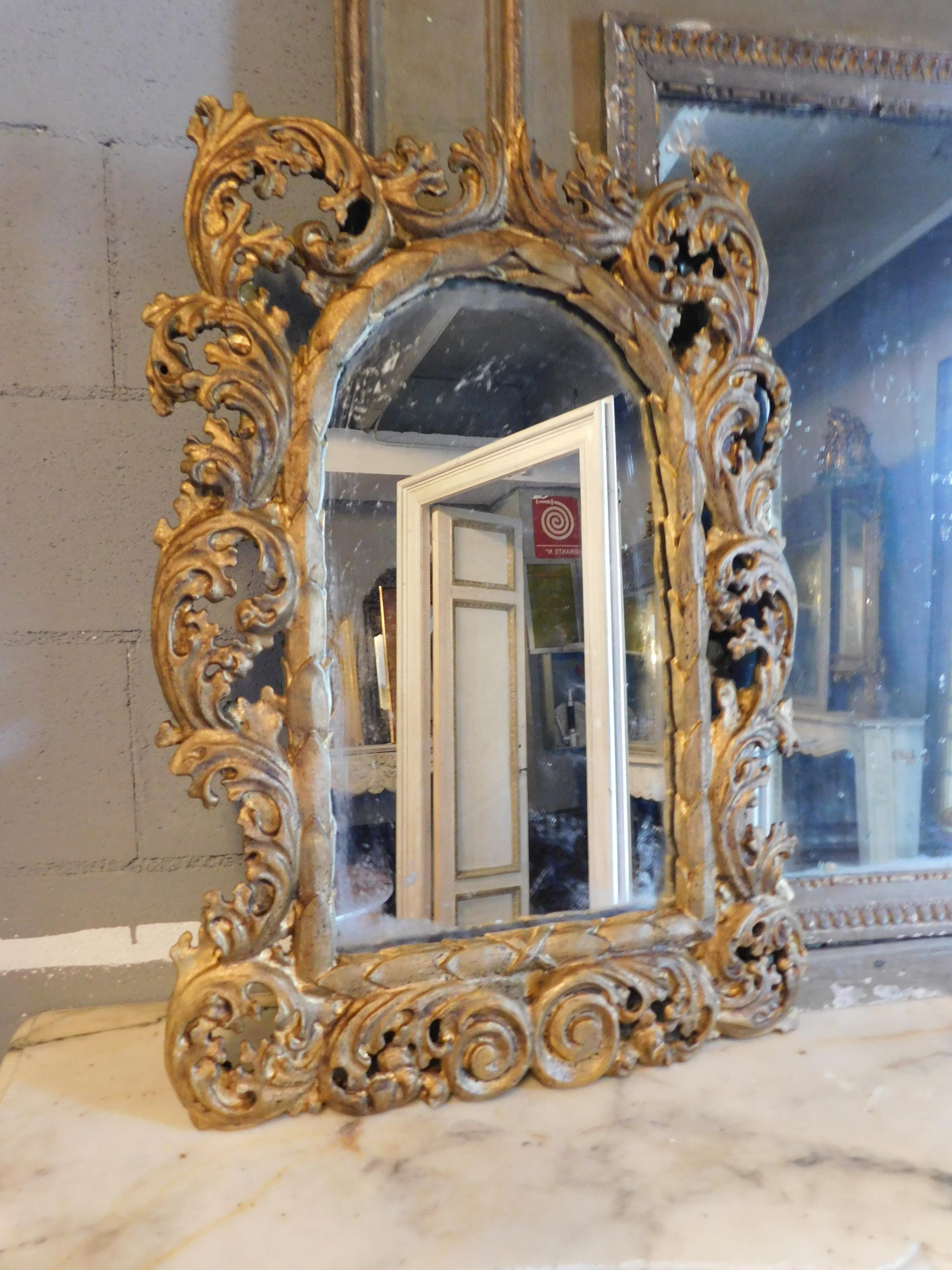 Antique golden mirror, richly carved with scrolls and curls, typical decorations of the eighteenth century, from Italy, in good conservation conditions and with great scenic effect, ideal for bathrooms, over fireplaces, living rooms or interiors of