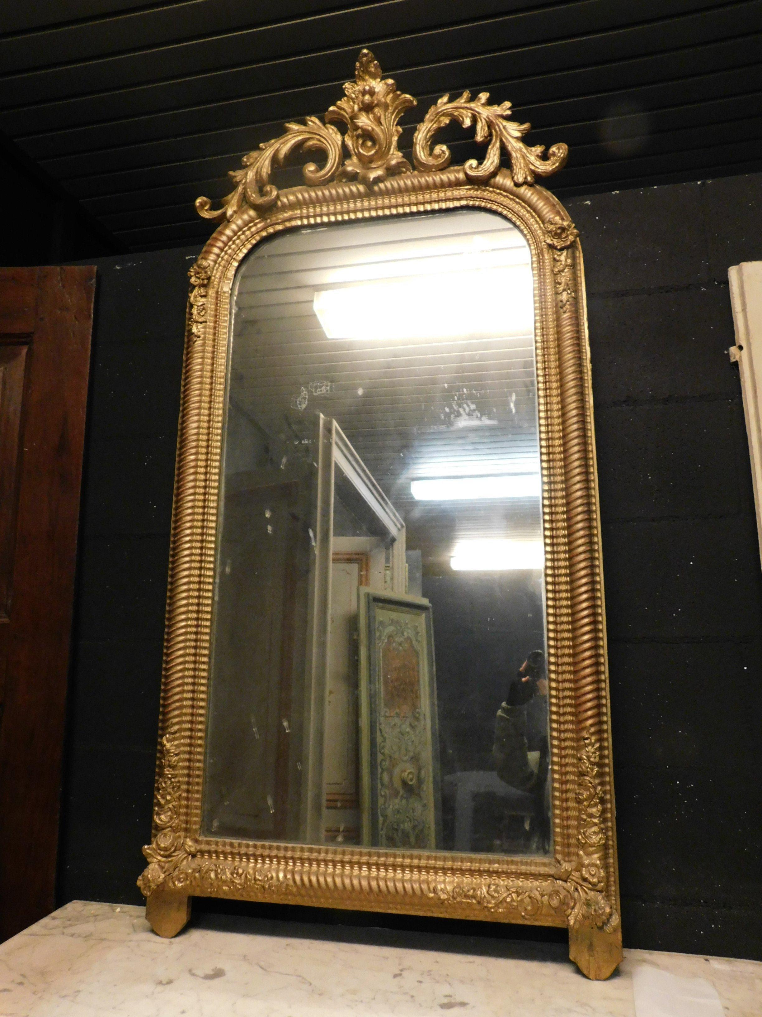 Antique mirror in gilded wood with carved rib, floral motifs in the upper part and carved frame, very rich and beautiful also maintaining a linear geometric shape that can be adapted to all uses and interiors, built entirely by hand in the 19th