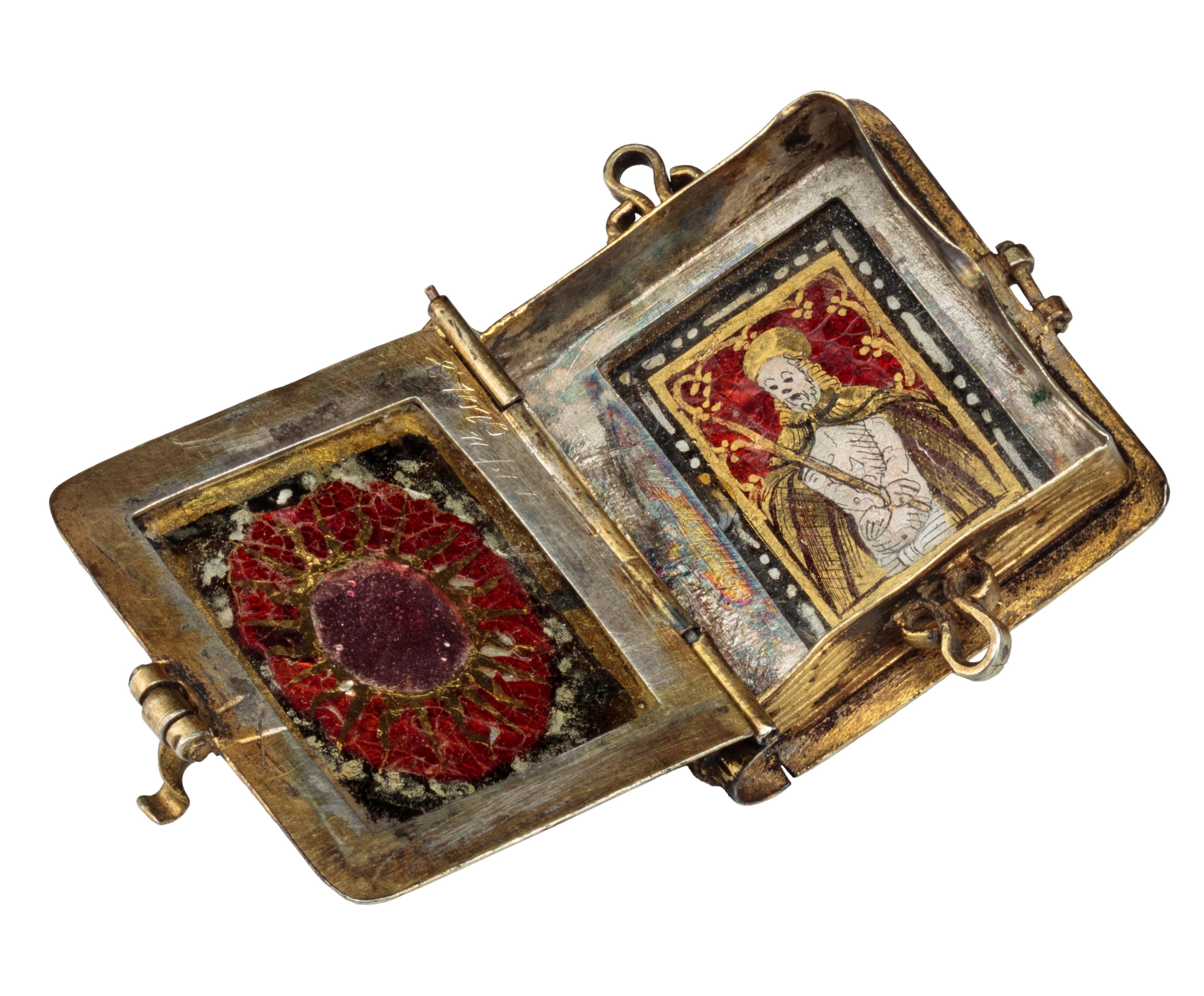 Reliquary Pendant in Book Form
Southern Germany, probably Augsburg, c. 1550 
Gilded silver, verre églomisé 
Weight 14.1 grams; dimensions 35 × 29 × 13 mm 

Gilded silver pendant in book form with hinged lid, corded wire surround, and engraved spine.