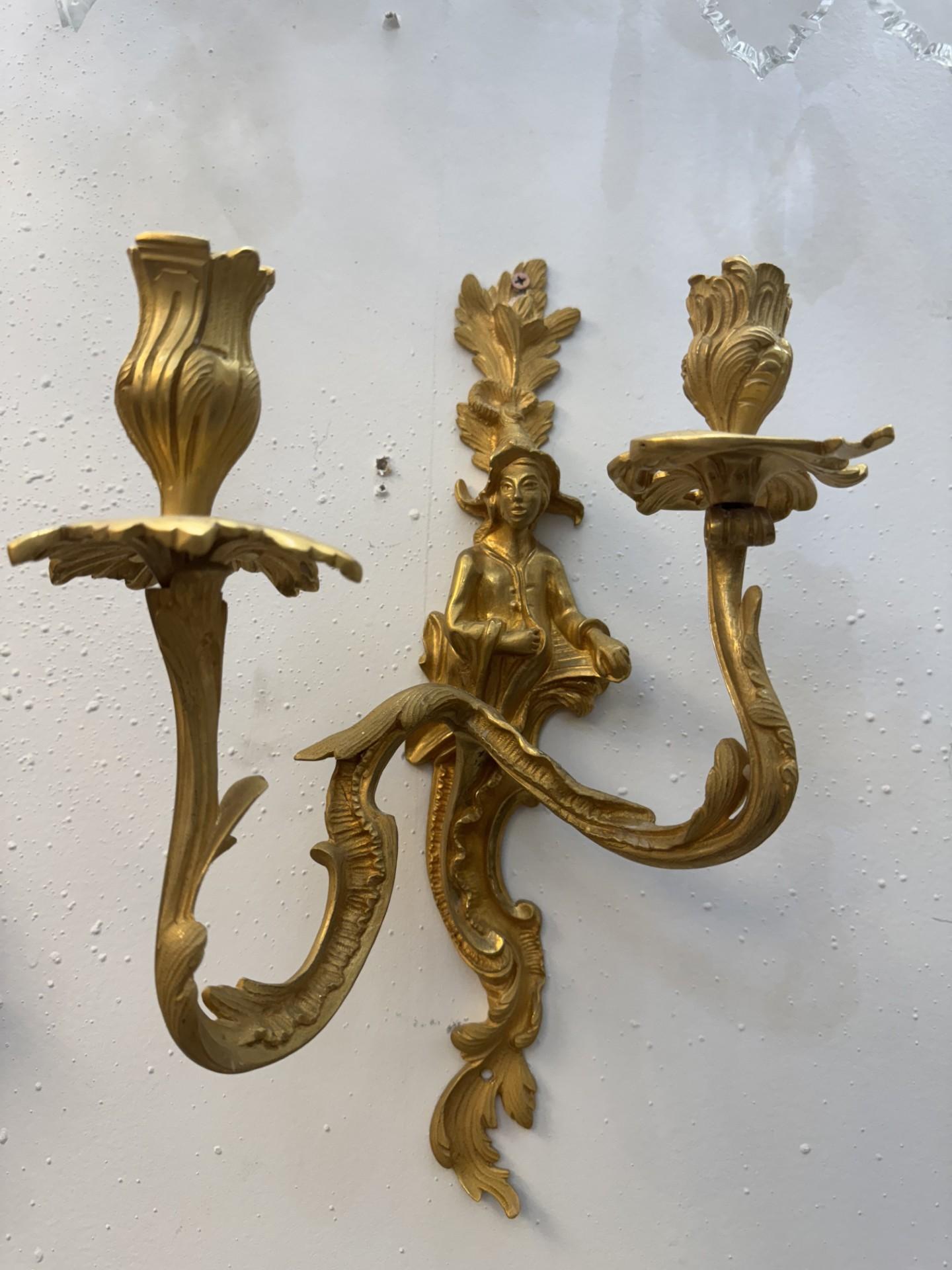 Pair of Wall sconces featuring an ornate gilded finish with beautifully detailed female or male figurines at the center. Each sconce holds two candlestick lights with petal-shaped holders, adding a classic and romantic touch. These traditional style