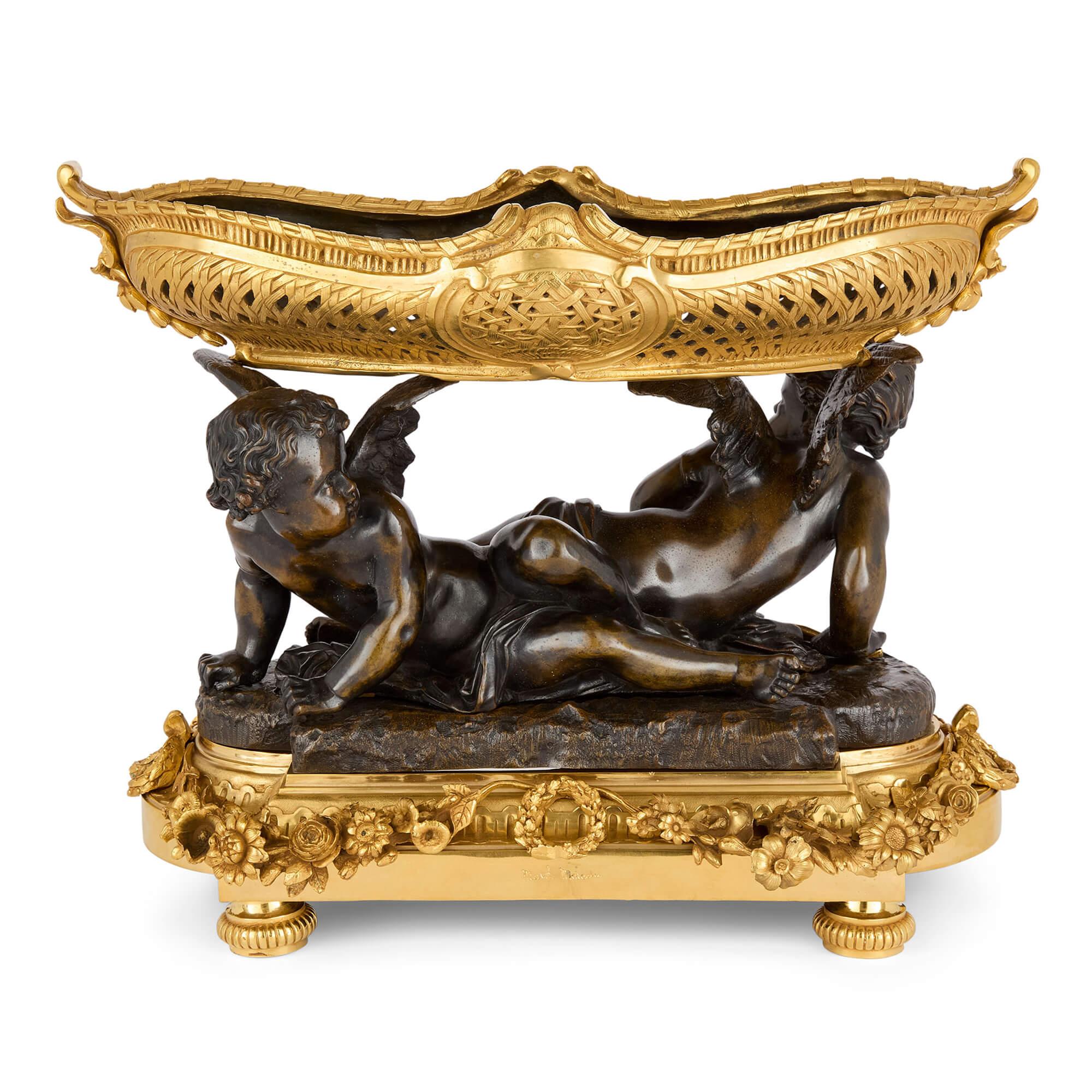 Antiguo centro de mesa querubín de bronce dorado y patinado de Moreau
Francés, siglo XIX 
Altura 38 cm, anchura 50 cm, profundidad 27 cm

Este excepcional centro de mesa de estilo Luis XVI es obra del estimado escultor francés Mathurin Moreau