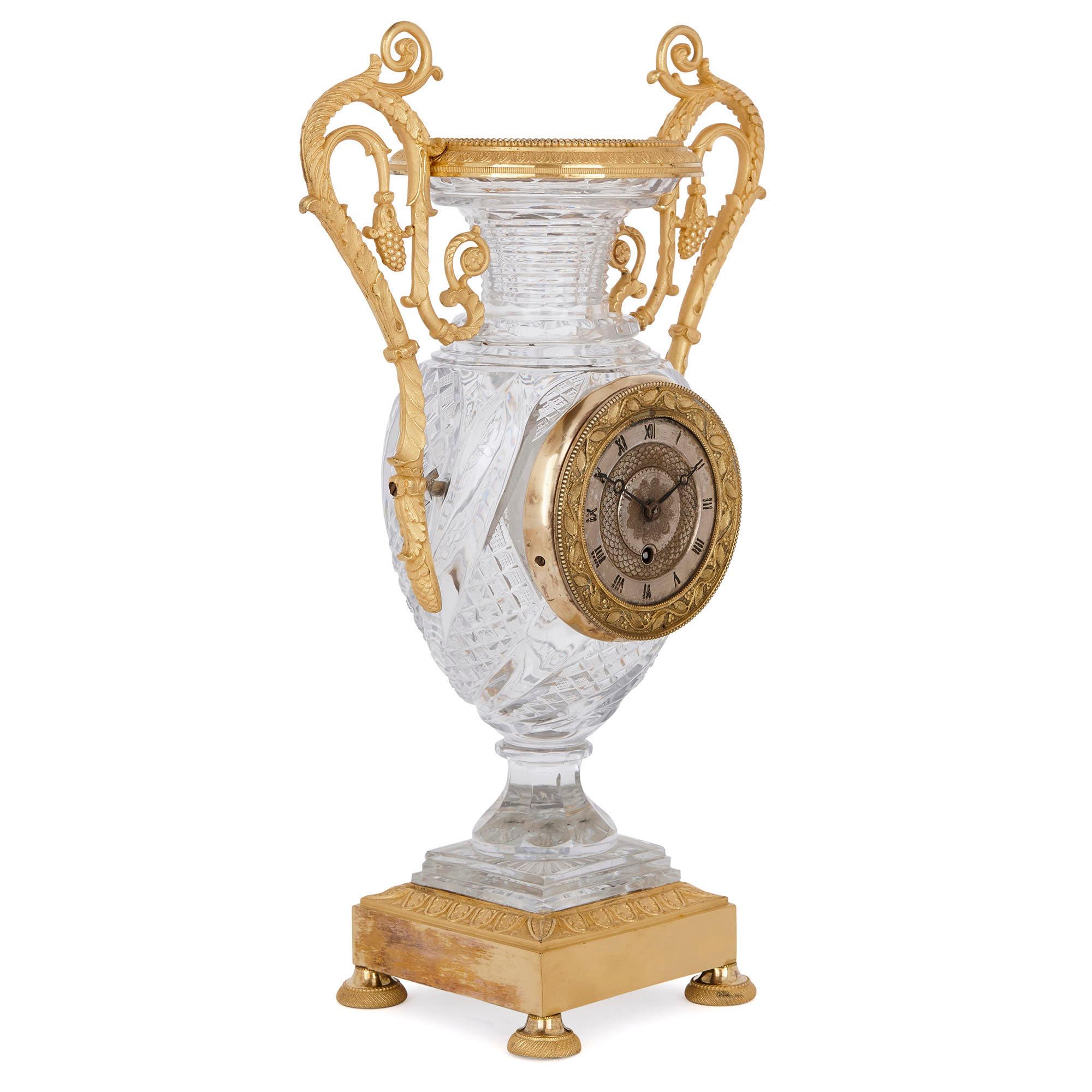 Ce gracieux ensemble d'horloges à trois pièces est conçu dans un style néoclassique raffiné, qui était à la mode en France au XIXe siècle. L'ensemble a été fabriqué à partir de verre transparent finement taillé et monté dans un bronze doré (ormolu)