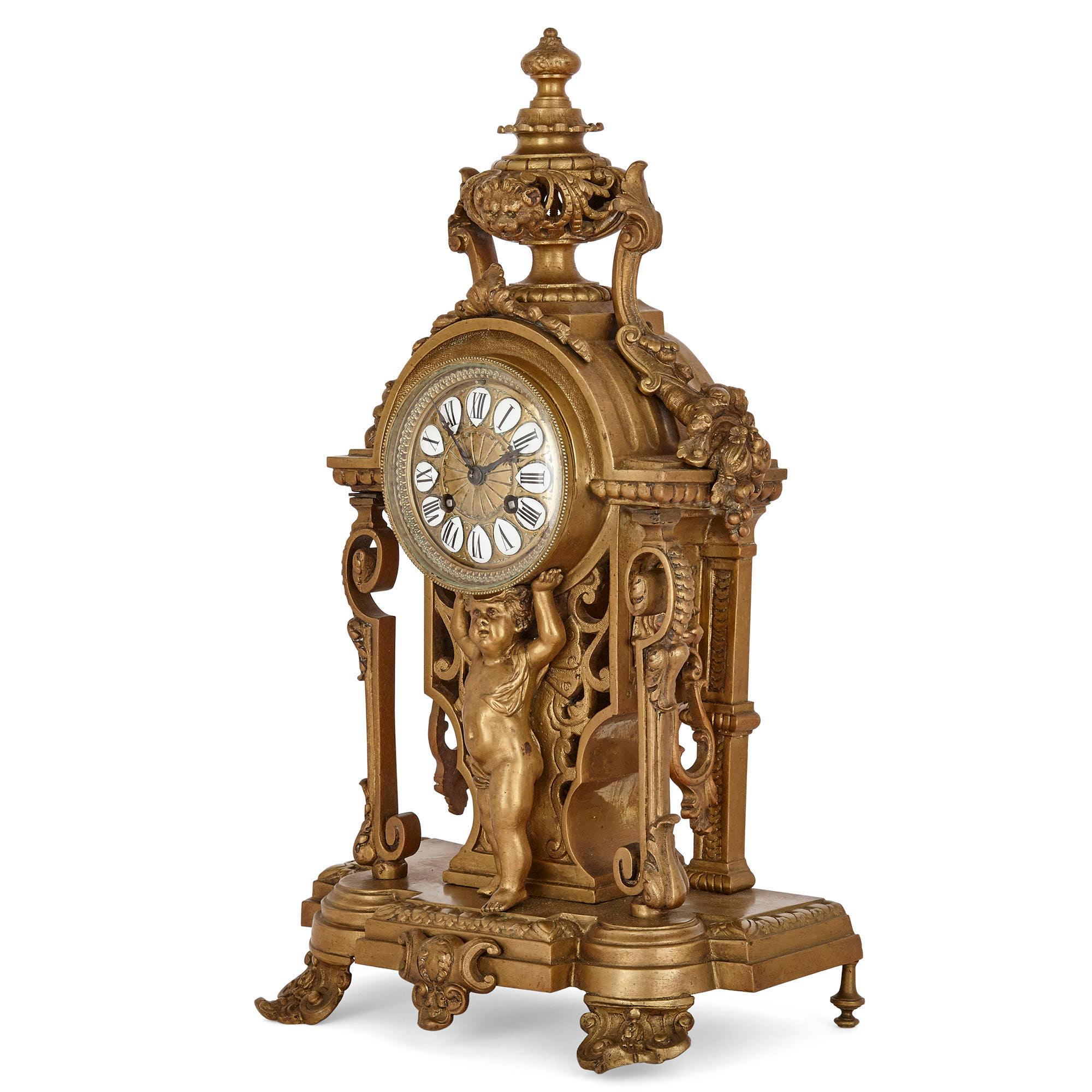 This clock set contains a mantel clock and a pair of candelabra. Unusually, the clock and candelabra are constructed entirely of gilt bronze. The bronze dial of the mantel clock is inscribed with Roman numeral hours on separate enamel cartouches.