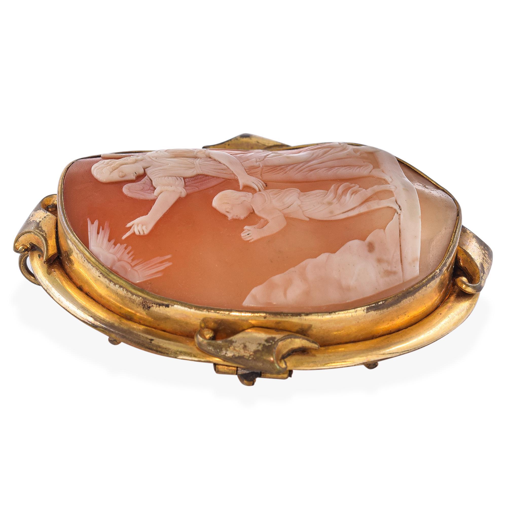 Ce pendentif broche en camée en coquillage datant du milieu du XIXe siècle présente une tendre représentation d'un ange gardien veillant sur un enfant, symbolisant la protection et l'attention divine. Sculptée à la main et placée dans un cadre doré,