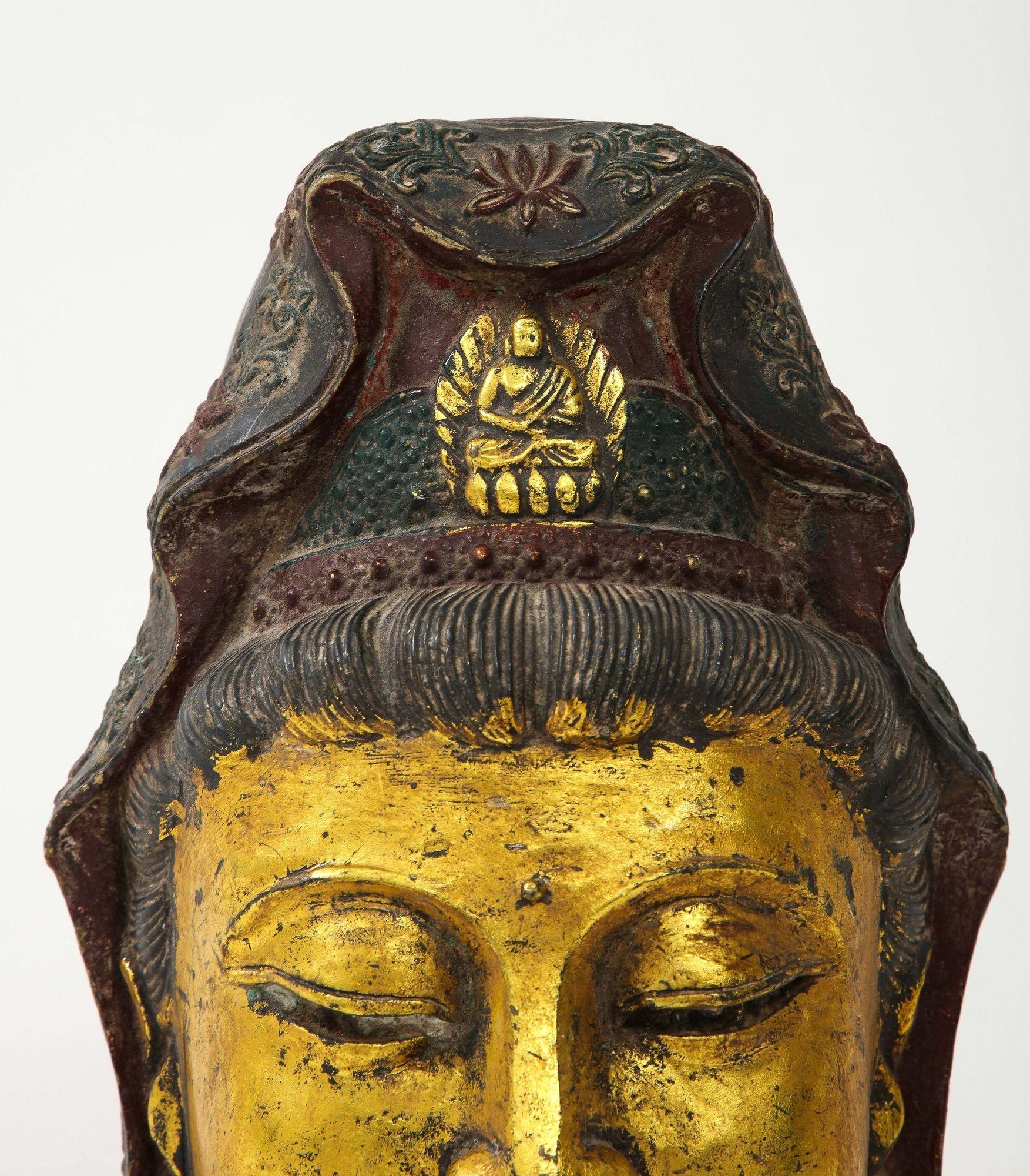 A striking gilt iron metal Buddha head, a piece that exudes a sense of serene power and spiritual elegance. The head is meticulously crafted from iron, a robust material that lends a sense of enduring strength. The gilding, applied with care,