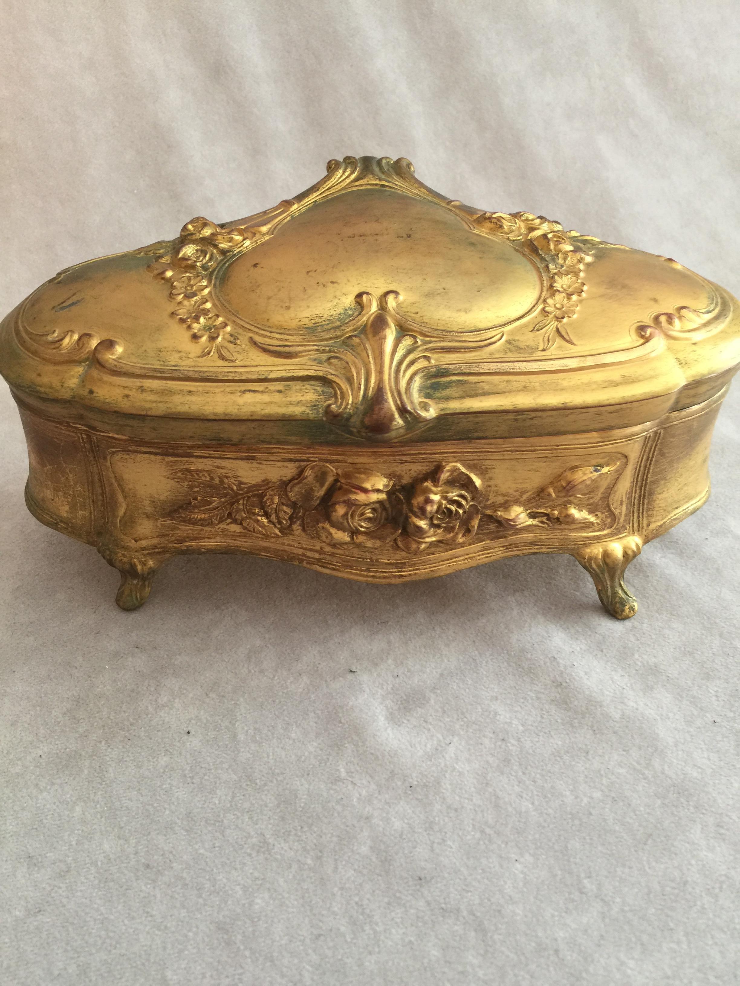 This richly gilt metal jewelry box makes a perfect gift for the lady in your life, in other words, no thought required. She will love it. Done in the art nouveau style with grace and beauty. It even has a heart on the cover for that extra touch.
