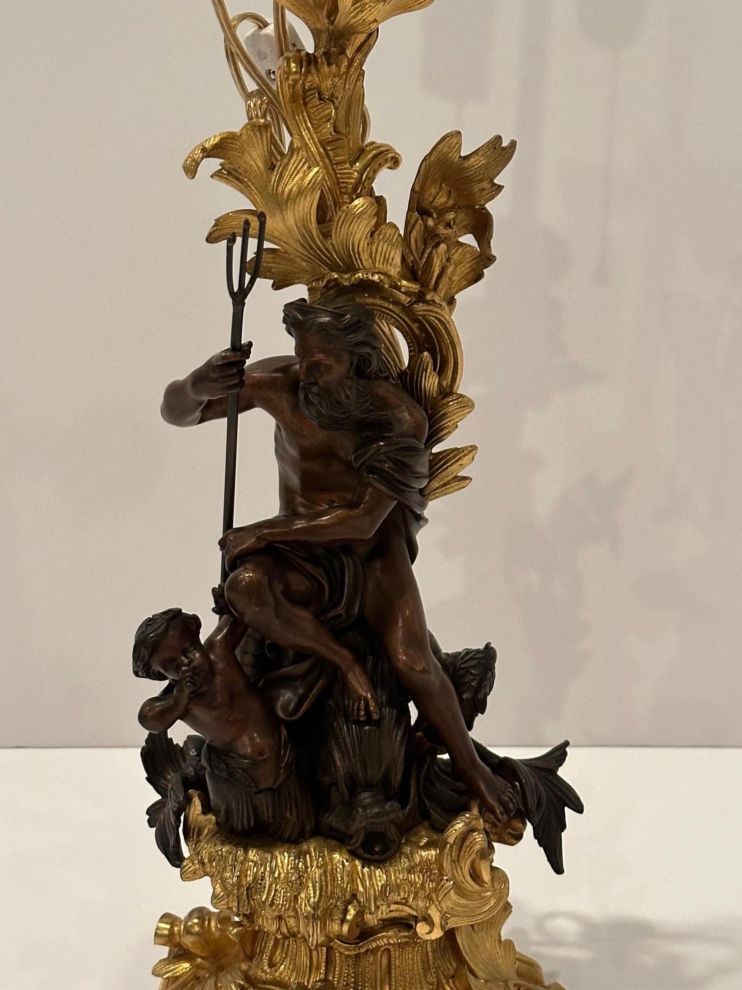 Chandelier sculptural transformé en lampe de Neptune avec fourche assis sur un dauphin et une sirène.  Un mélange de bronze foncé patiné et de bronze doré brillant constitue une œuvre d'art ornée et splendide.  Les détails sont