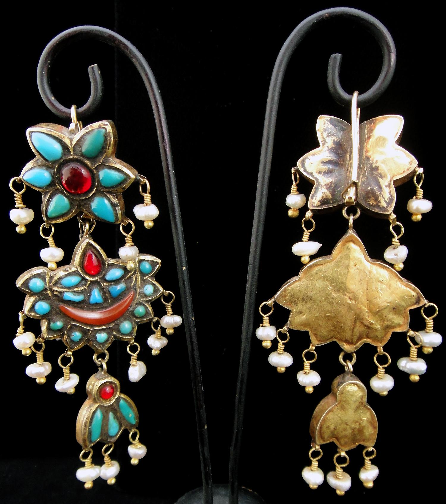 These lovely antique earrings are from Afghanistan. Made of hollow from gilt silver segments, they are adorned with turqoise, glass, carnelian and pearls. Gilt silver, sometimes known in American English by the French term vermeil, is silver which