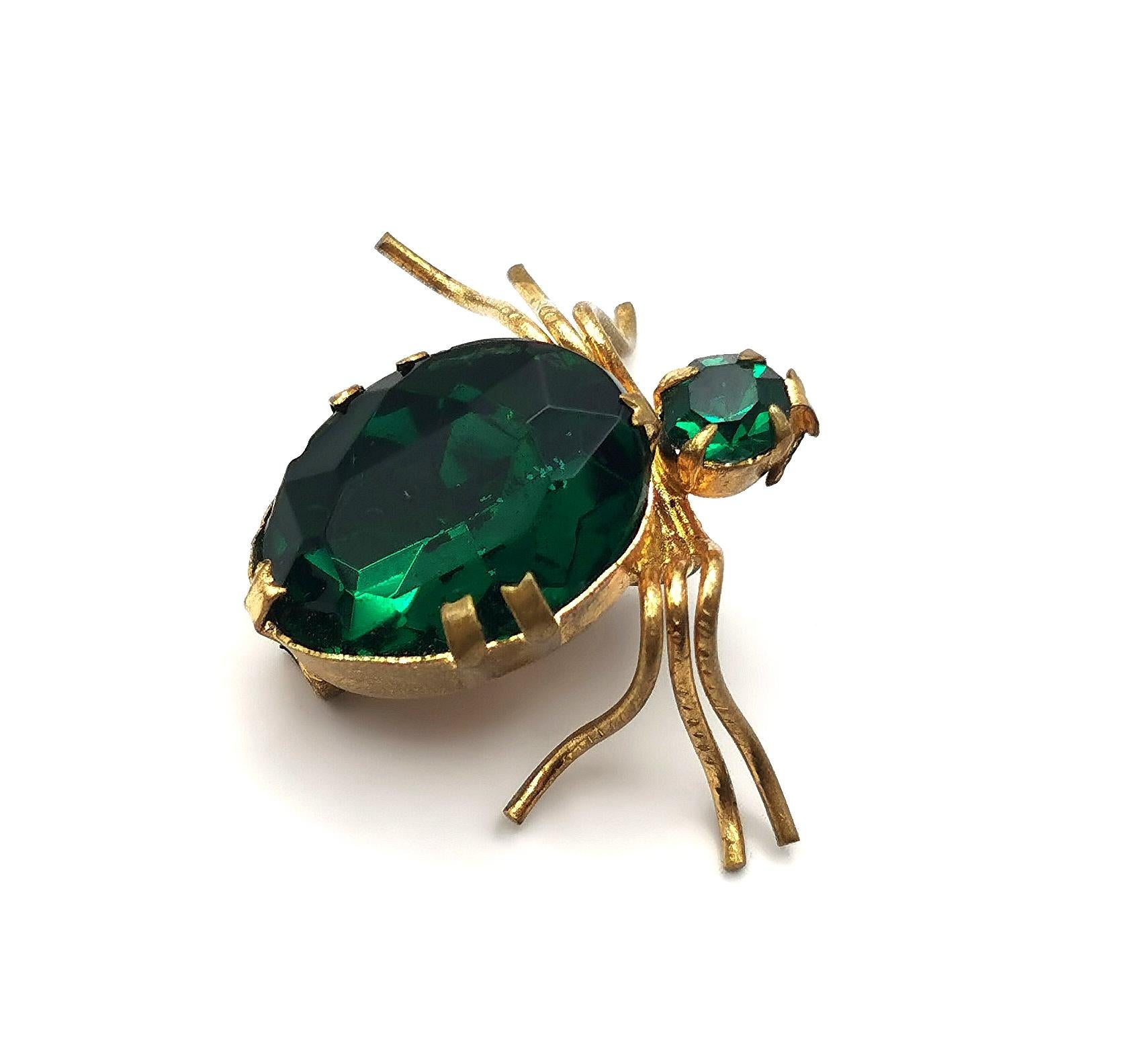Une jolie broche en forme d'araignée datant de l'époque édouardienne.

Réalisée en métal doré, elle est ornée d'une pierre ovale en pâte vert émeraude foncé sur le corps et d'une autre sur la tête.

Oui, il s'agit d'une araignée à six pattes ou