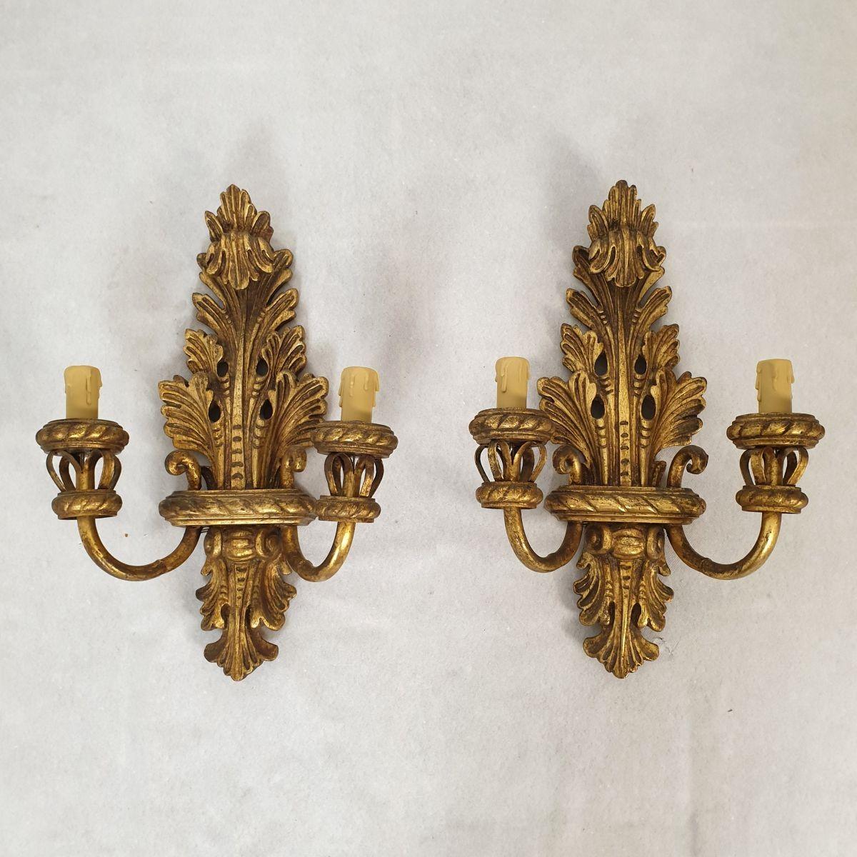 Pair of antique gilt wood wall sconces, France 1920's.
The sconces have a large size and are in excellent condition.
They are made of git wood, carved with a neoclassical decor and style.
The arms are made in gilt iron.
Each sconce has 2 lights and